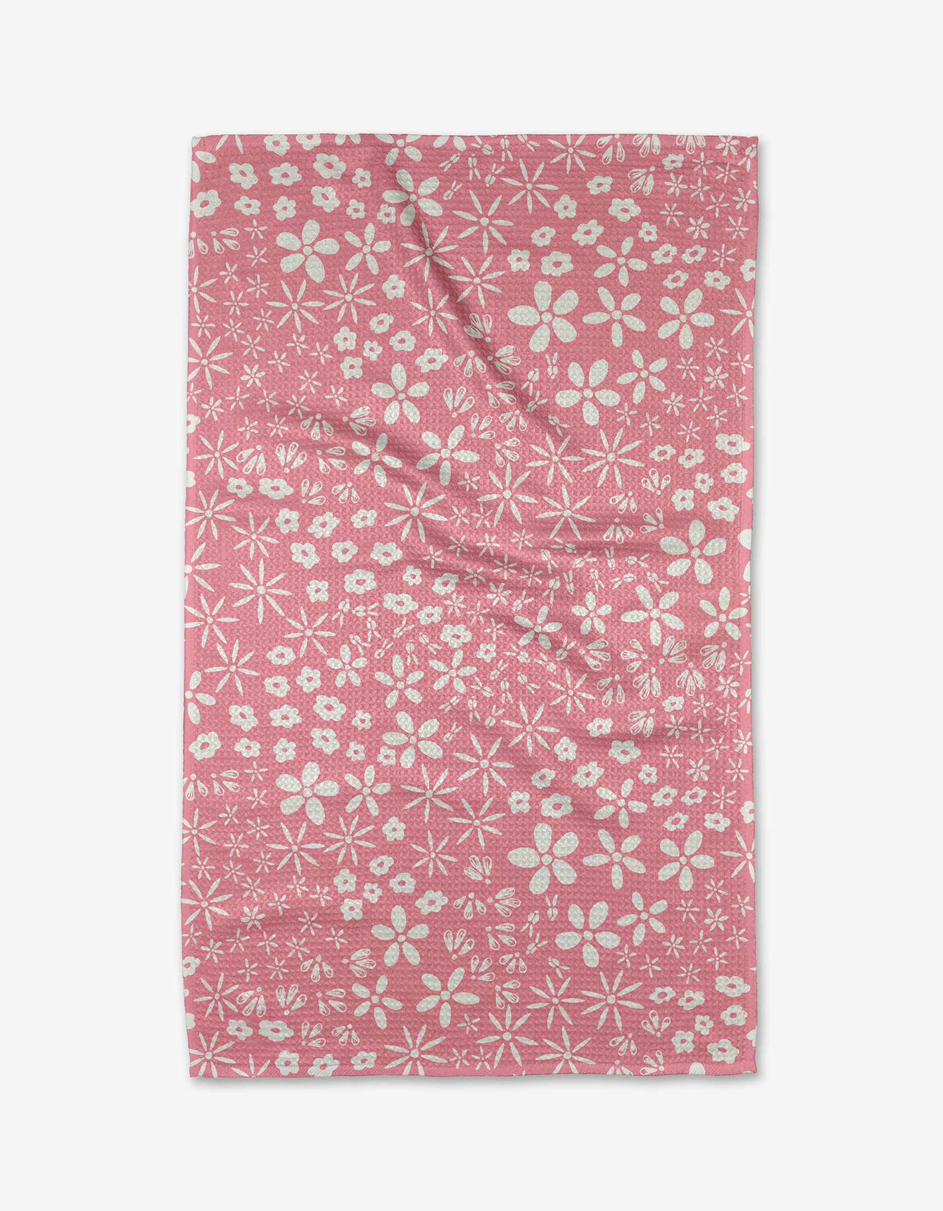 The Field of Flowers tea towel by Hufton Studio features a pink background with white flowers and star designs, made from recycled materials and shown flat with subtle wrinkles.