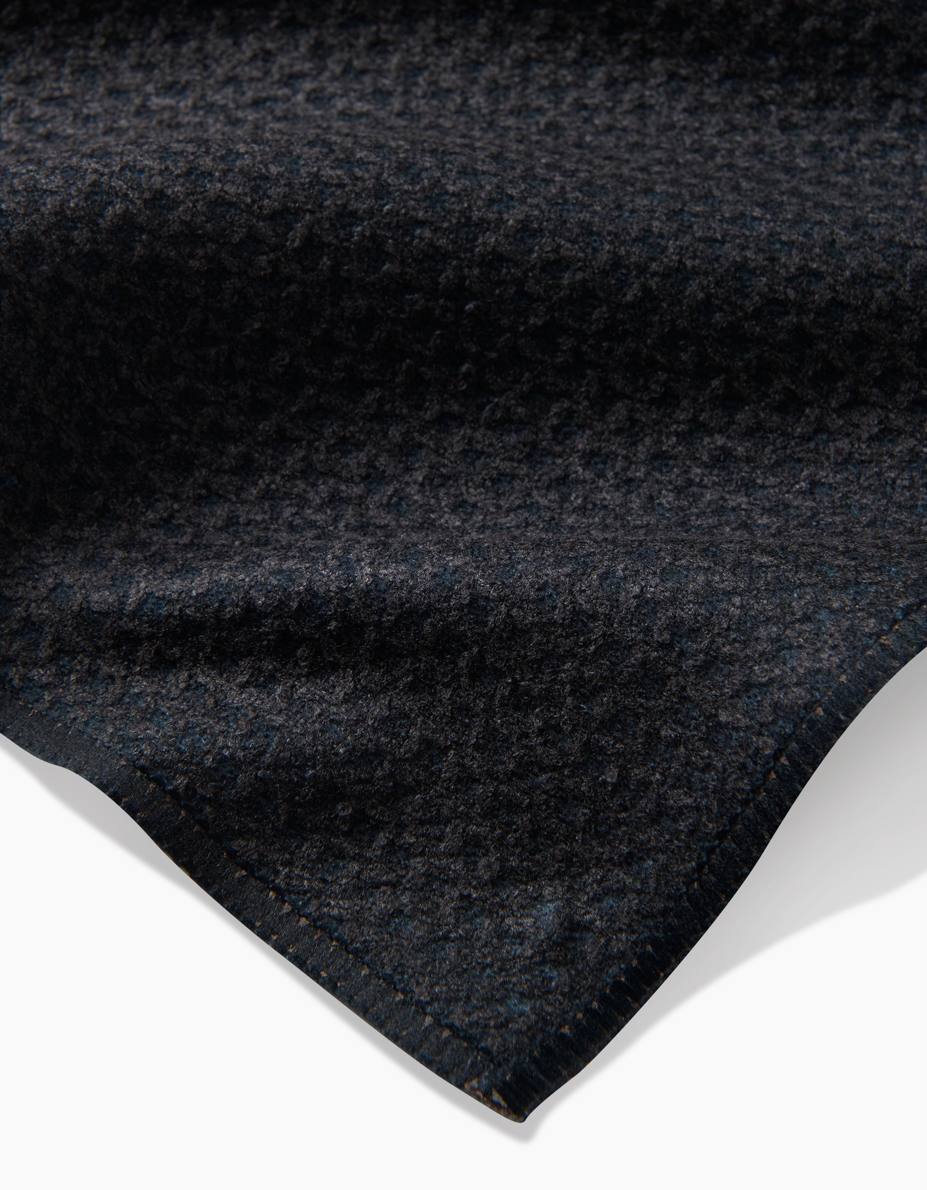 A close-up of the Fika tea towel by Anna Christian shows its dark, textured Geoweave™ fabric with a subtle geometric pattern and neat edge, set against a white background.