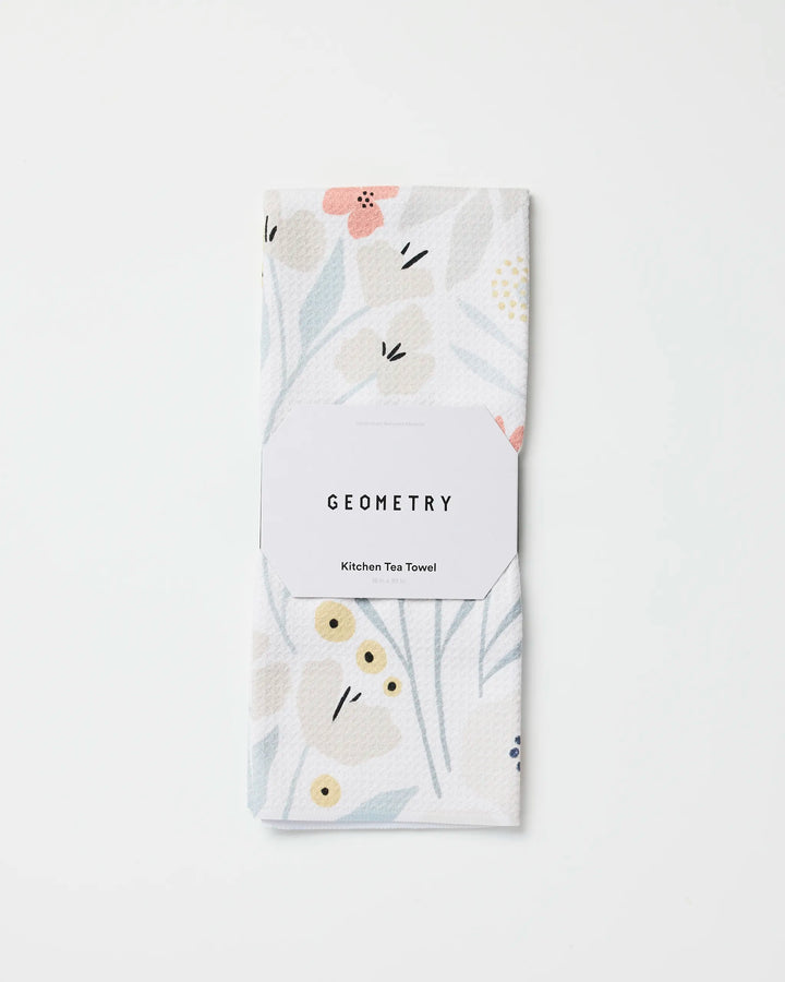 A folded white ultra-absorbent kitchen towel with a subtle floral pattern in soft pastels, labeled "Amy MacCready Fiona Cream," made from recycled materials and set against a plain white background.