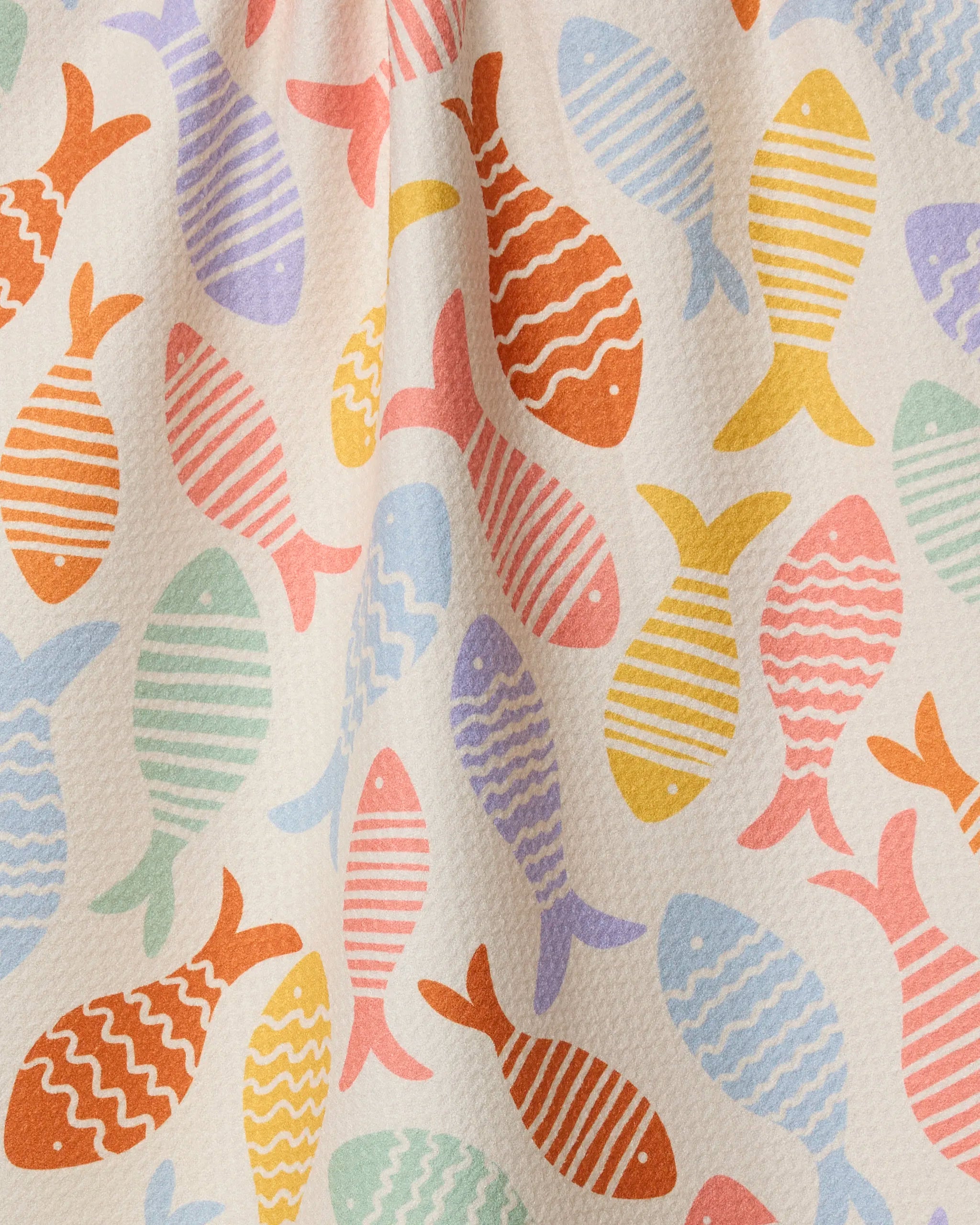 The Geometry Fish Flip recycled kitchen towel features a vibrant fish pattern in orange, yellow, blue, green, and pink with stripes or waves on a light background. Ultra-absorbent, this towel may appear slightly wrinkled.