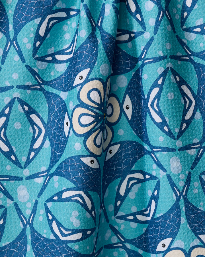Close-up of Marta Harvey's Fish Mandala tea towel, showcasing a vibrant aquatic-themed design with blue and turquoise stylized fish, geometric shapes, and white spots on quick-drying recycled fabric.