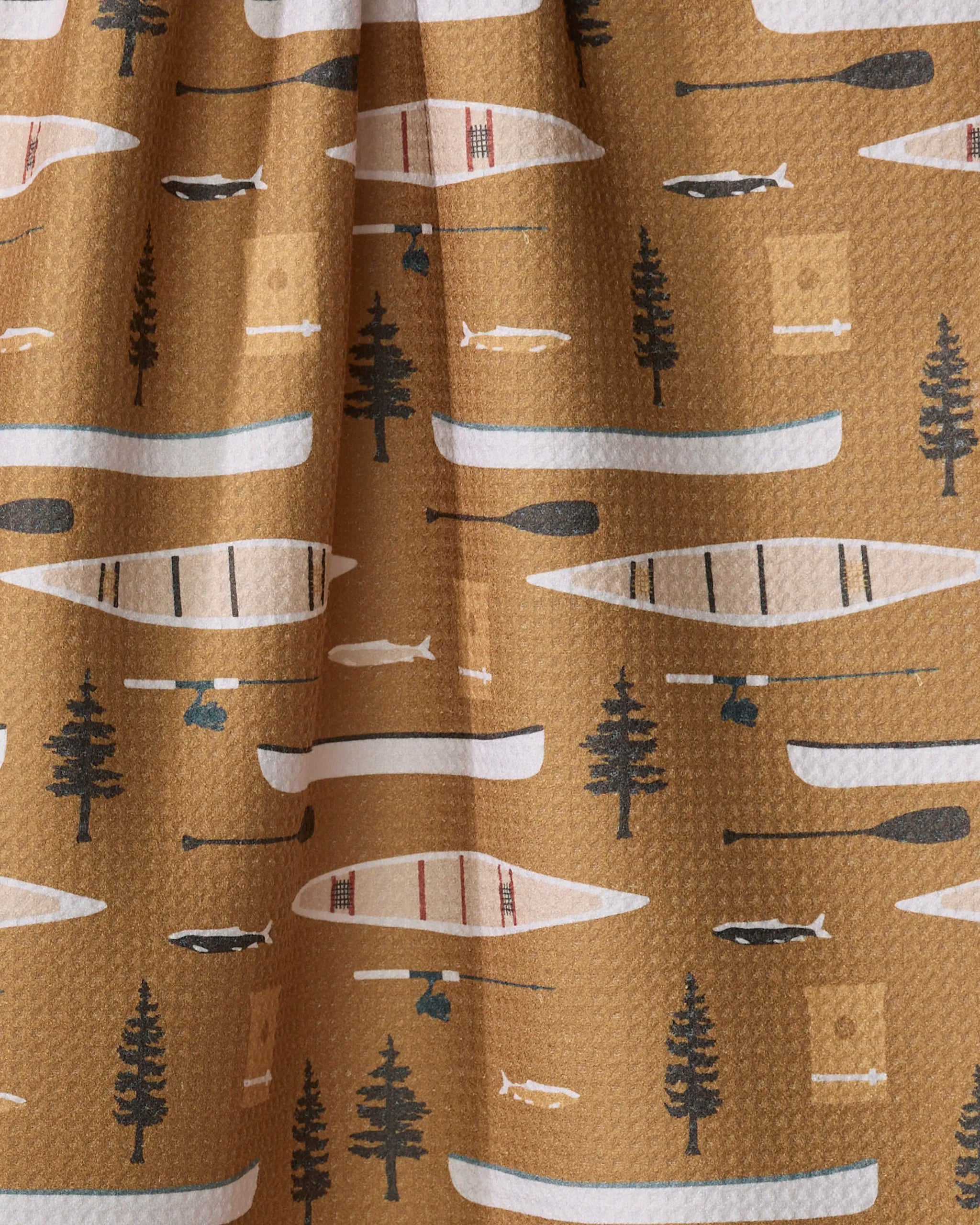 The "Fishing On the Lake" recycled kitchen towel by Coit Creative features a brown background with a repeating pattern of canoes, paddles, pine trees, fish, and camp lanterns in white, black, blue, and green.