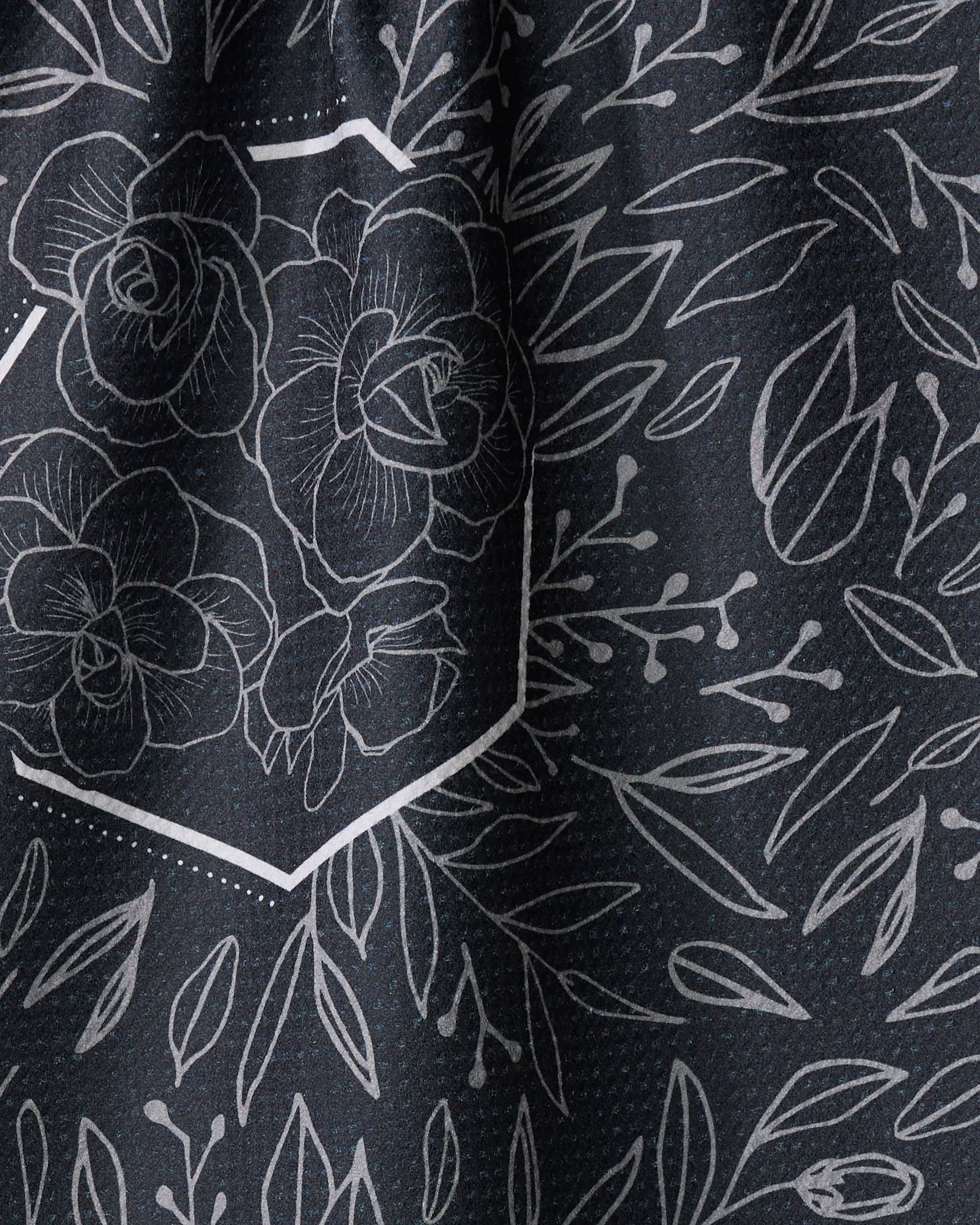 Close-up of Rosa Kichline's "Floral Explosion" black tea towel, crafted from recycled materials and adorned with white-outlined roses in hexagons alongside scattered leaves and branches.