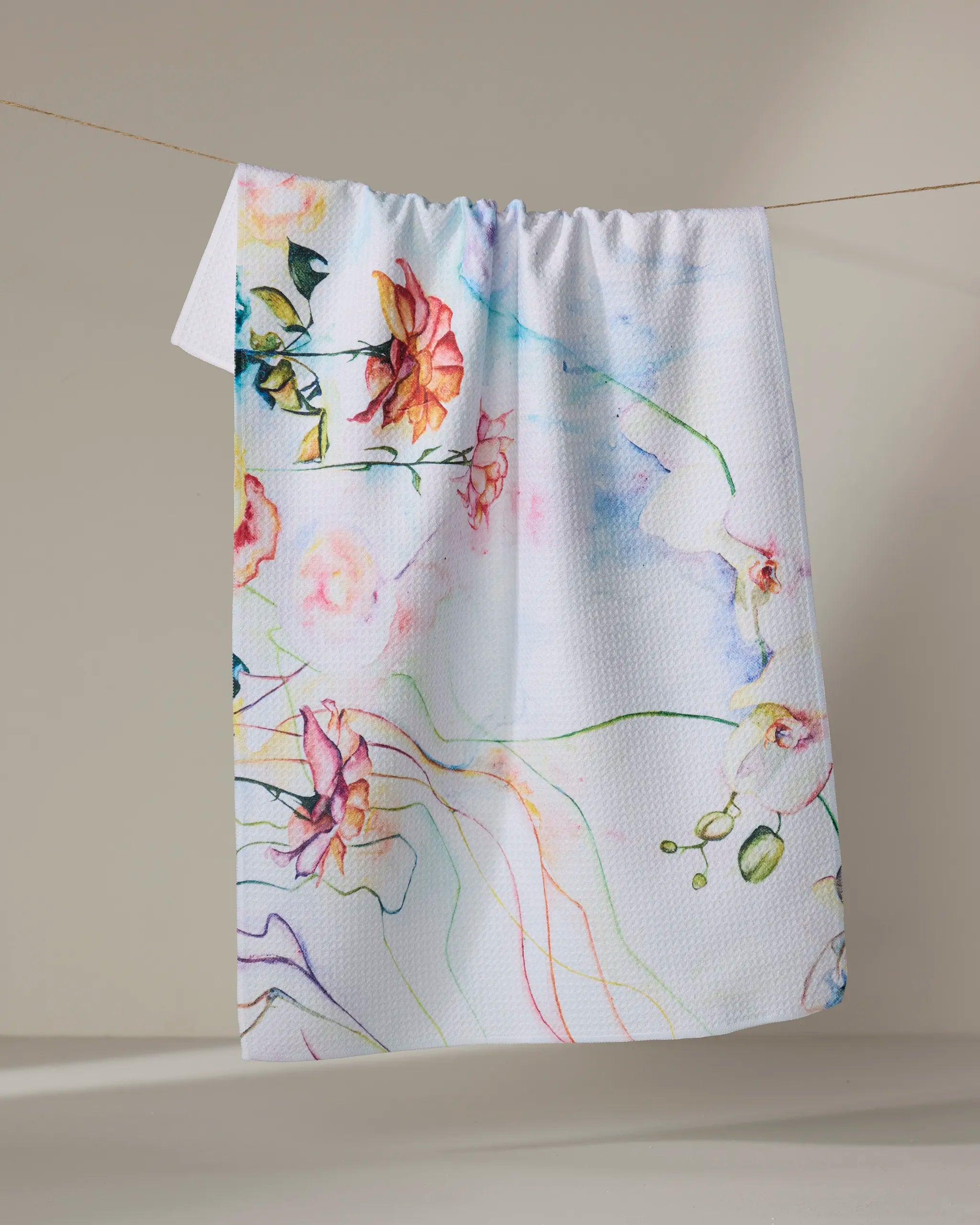 The Stefanie Bales "Floral Landscape" tea towel is a quick-drying white towel made from recycled materials, featuring colorful watercolor-style floral and abstract line designs.