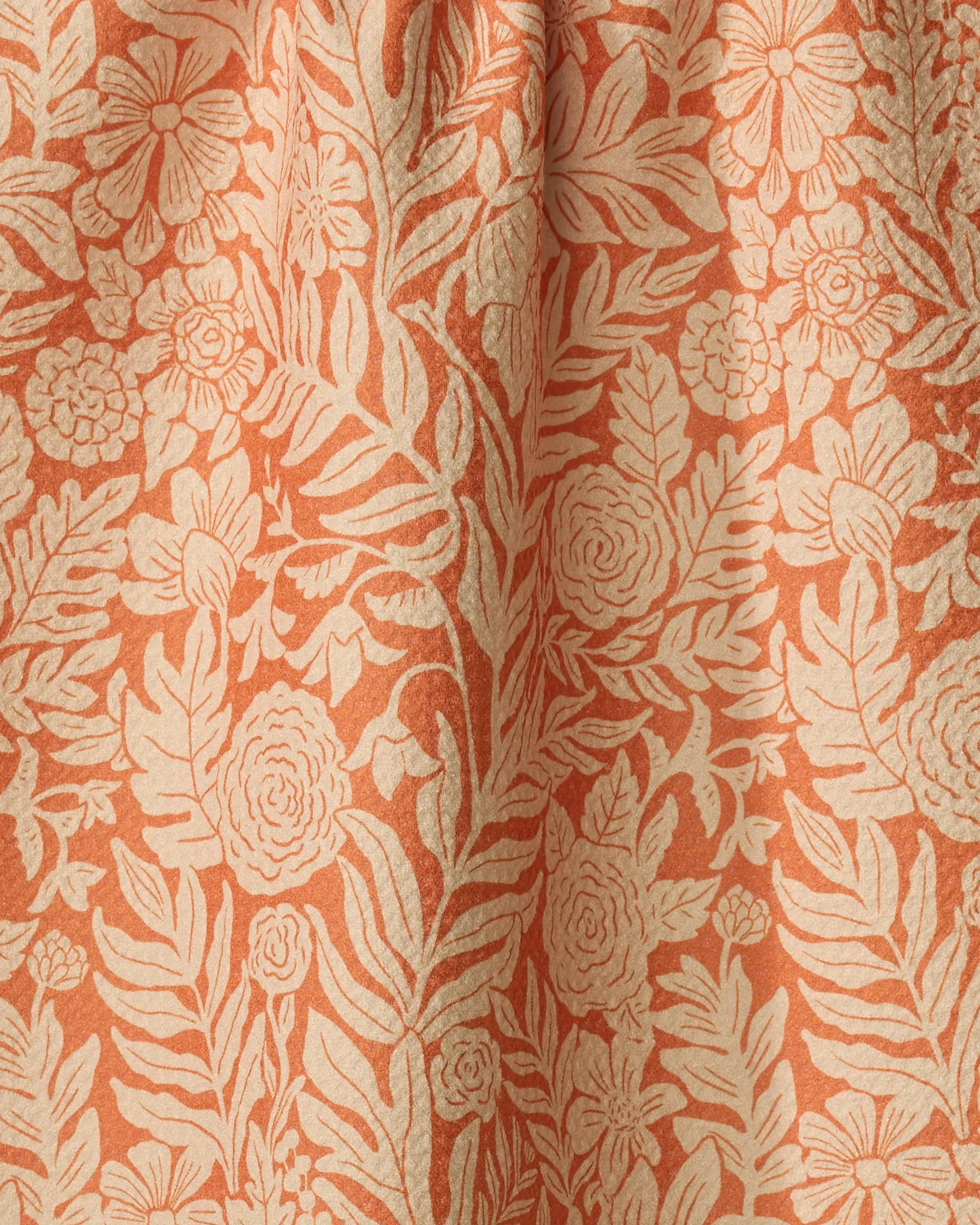 Close-up of the Florence recycled kitchen towel by Katie O'Shea, featuring an intricate cream floral and leaf pattern on a peach background. Softly draped with gentle folds, it's perfect as an absorbent dish or elegant tea towel.