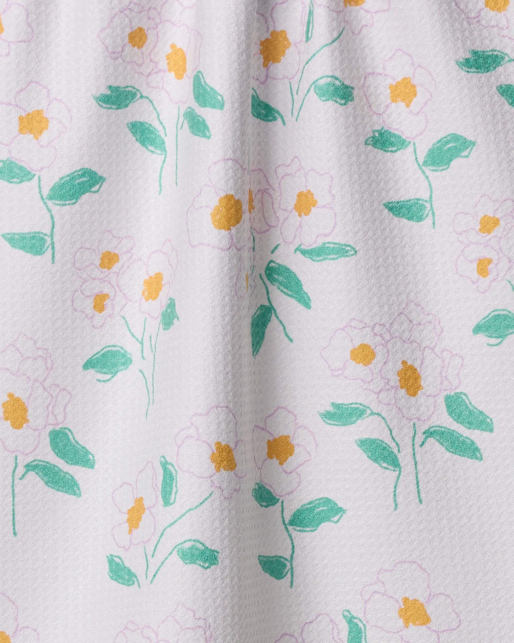 The Florista dish towel by Geometry features white textured fabric with a repeating pattern of light purple flowers, yellow centers, and green leaves. Simple and elegant, it's an absorbent, eco-friendly choice for everyday kitchen use.