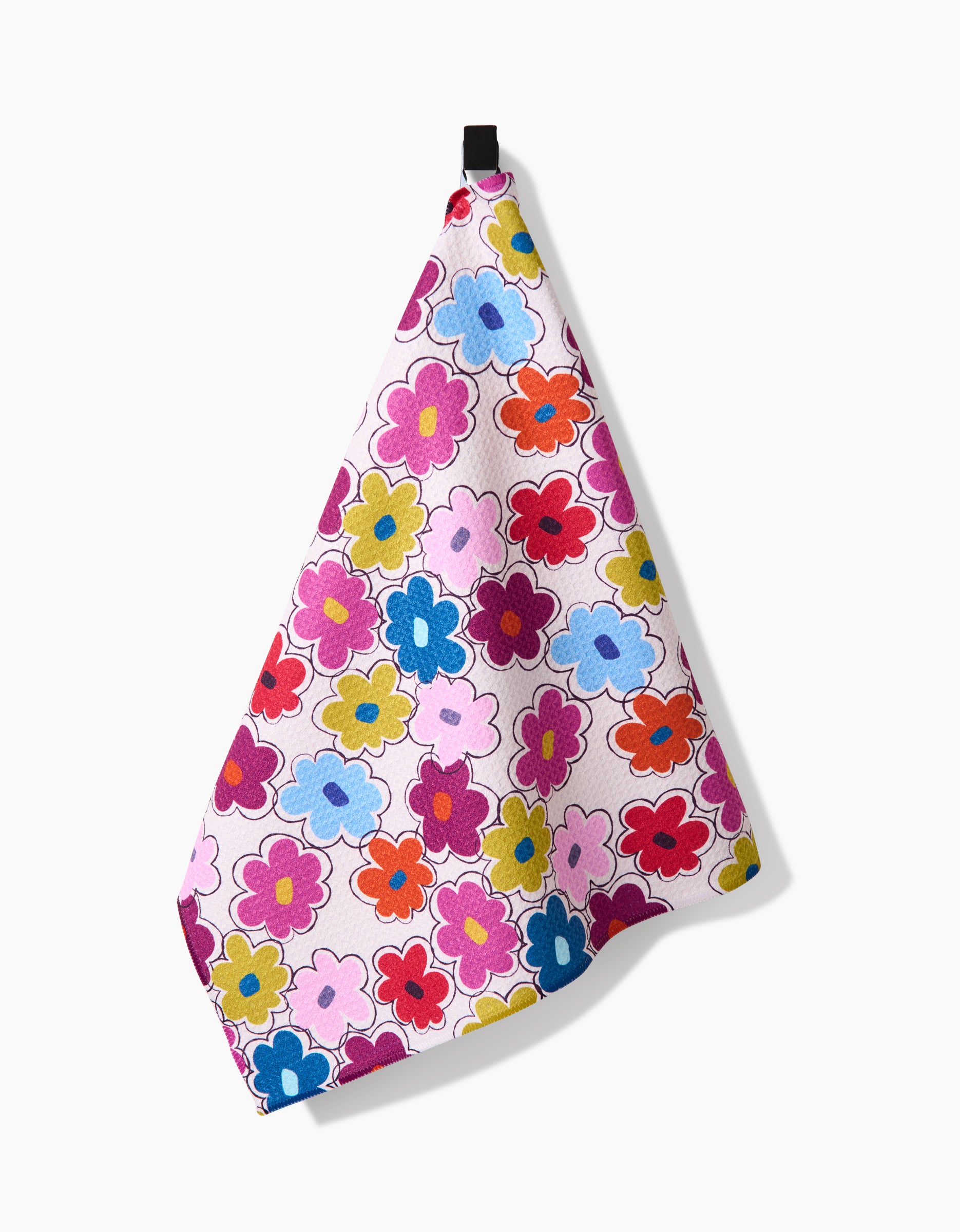The Lizzie Clark Flower Fling Tea Towel features a vibrant floral pattern in pink, red, yellow, blue, and purple on recycled fabric and hangs from a black loop against a white background.