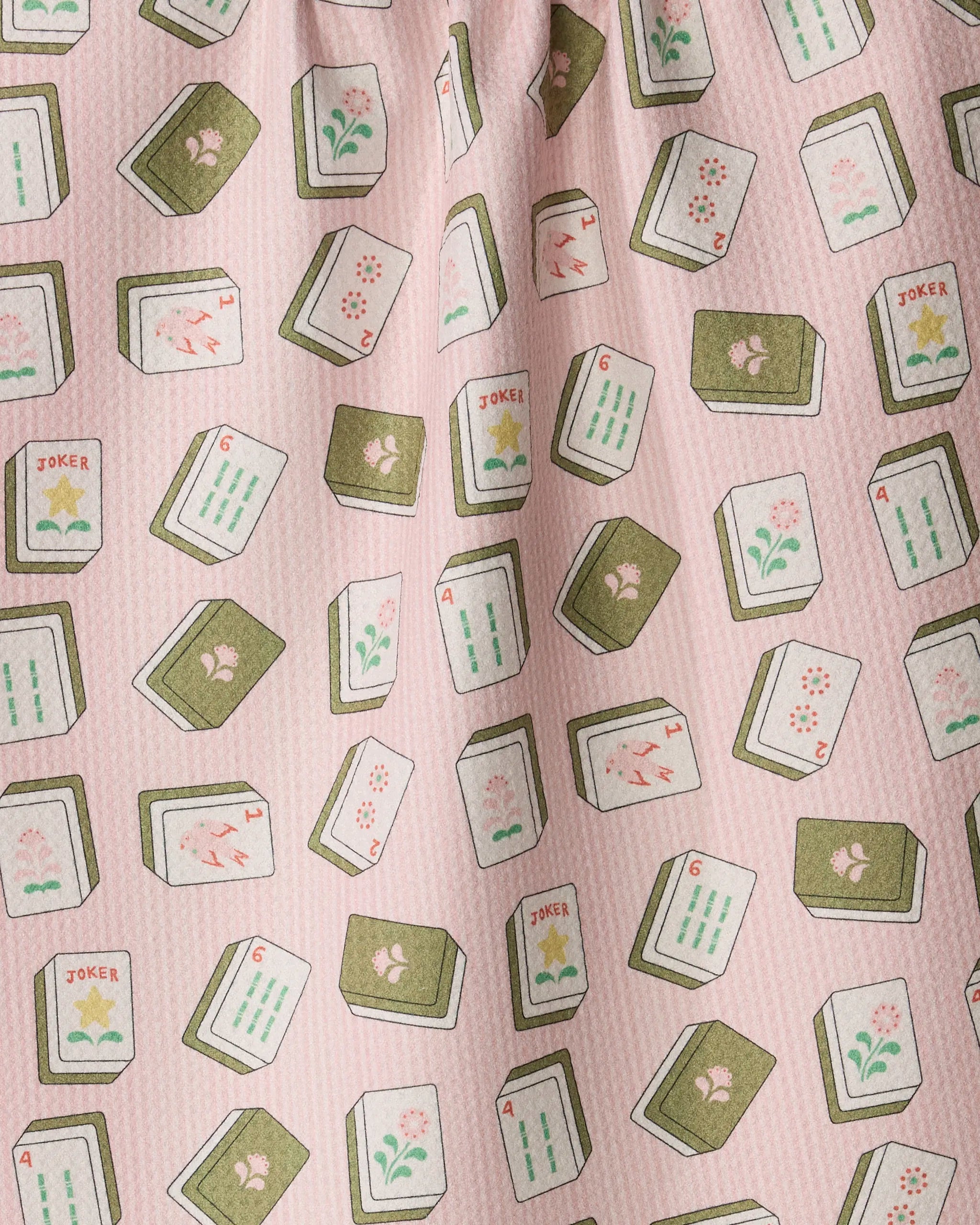 The Geometry "Flower Tiles" kitchen towel features a lively pink fabric adorned with an all-over print of illustrated mahjong tiles—including jokers and flower tiles—scattered playfully across the surface. Eco-friendly and quick-drying, this towel brings a cheerful, functional accent to your kitchen space.
