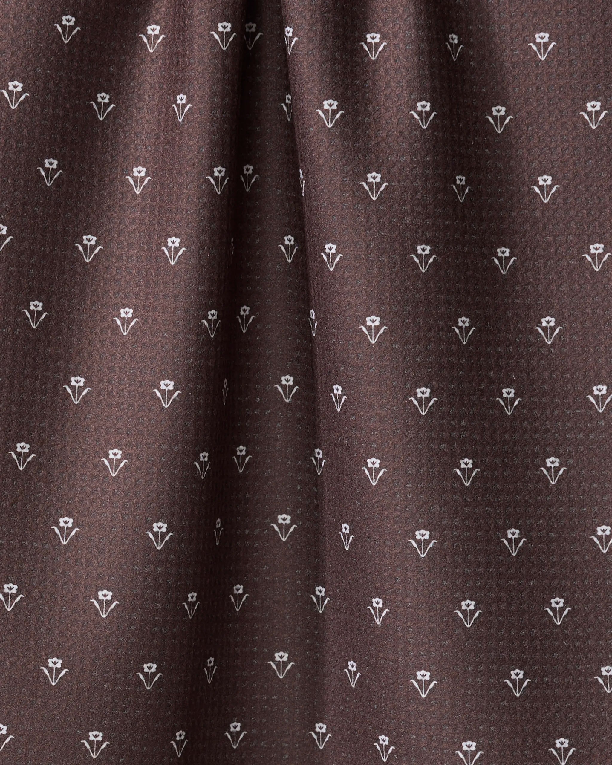 Close-up of The Buy Guide's Flowerfield Chocolate tea towel, featuring brown fabric with a repeating small white floral pattern for a subtle geometric look. This quick-drying towel appears soft and gently draped.