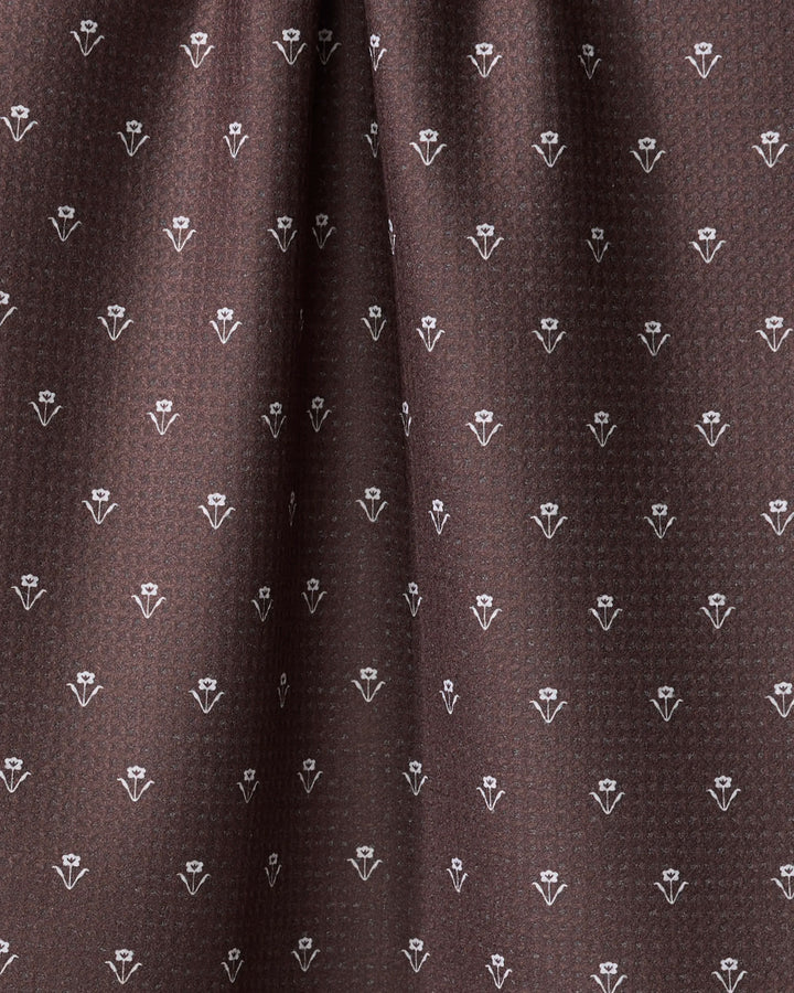 Close-up of The Buy Guide's Flowerfield Chocolate tea towel, featuring brown fabric with a repeating small white floral pattern for a subtle geometric look. This quick-drying towel appears soft and gently draped.