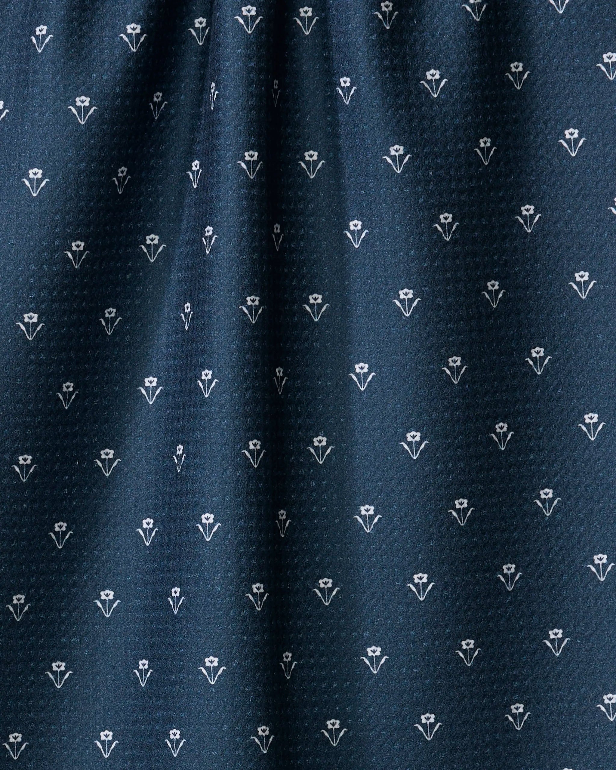 The Buy Guide's Flowerfield Navy tea towel features dark blue ultra-absorbent fabric with small white floral motifs in neat rows and a gently gathered top, adding subtle decorative texture to any kitchen.