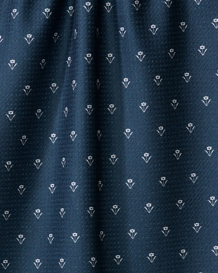 The Buy Guide's Flowerfield Navy tea towel features dark blue ultra-absorbent fabric with small white floral motifs in neat rows and a gently gathered top, adding subtle decorative texture to any kitchen.
