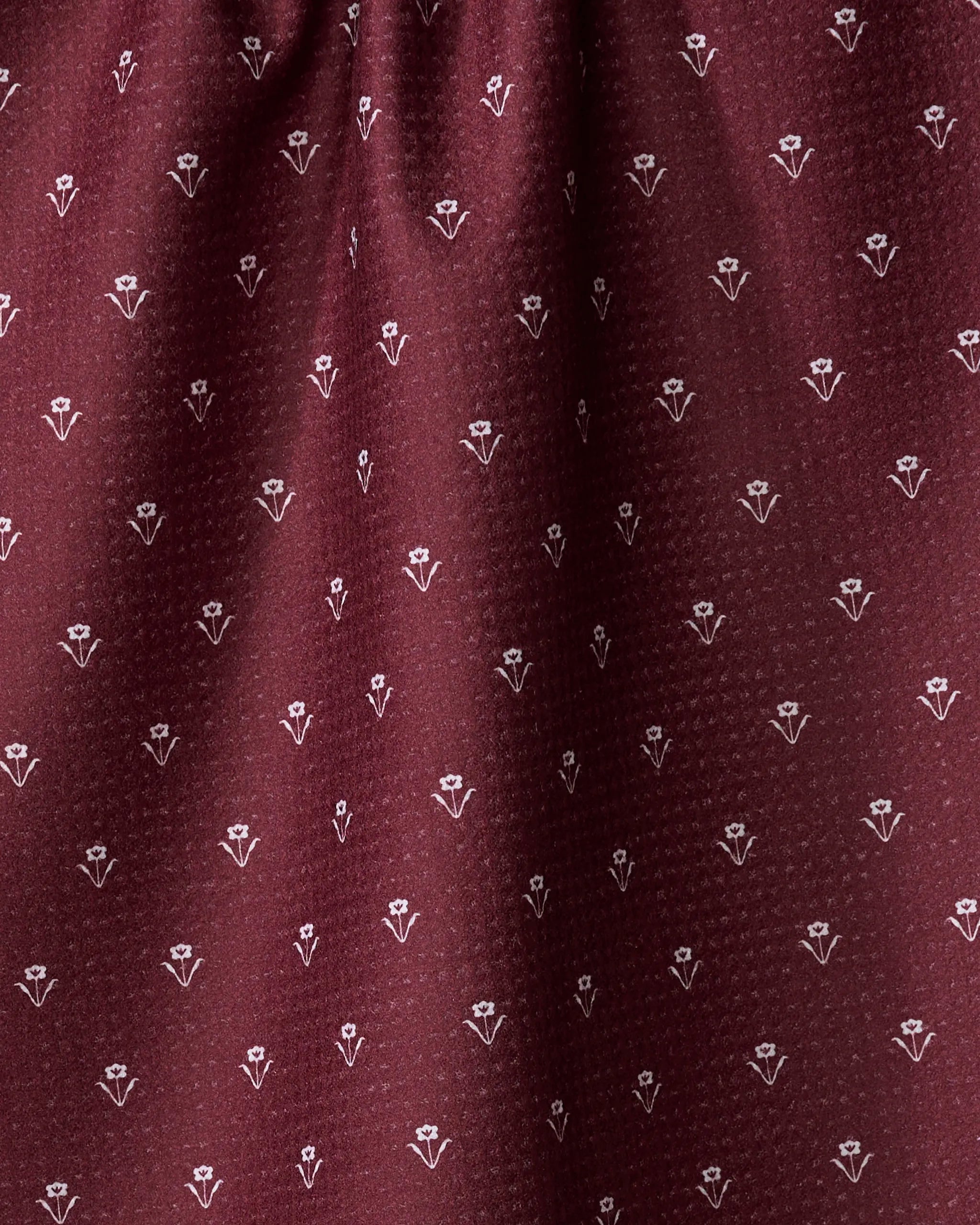 Close-up of the Flowerfield Wine fabric by The Buy Guide, featuring maroon dotted texture with repeating white floral motifs—an absorbent, eco-friendly dish towel perfect for daily kitchen use.