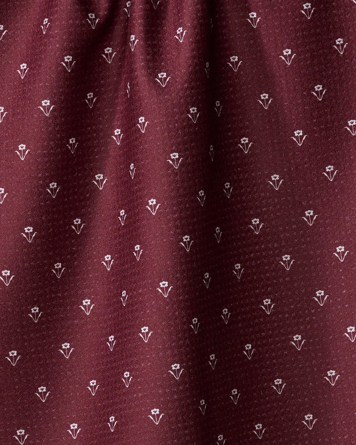 Close-up of the Flowerfield Wine fabric by The Buy Guide, featuring maroon dotted texture with repeating white floral motifs—an absorbent, eco-friendly dish towel perfect for daily kitchen use.