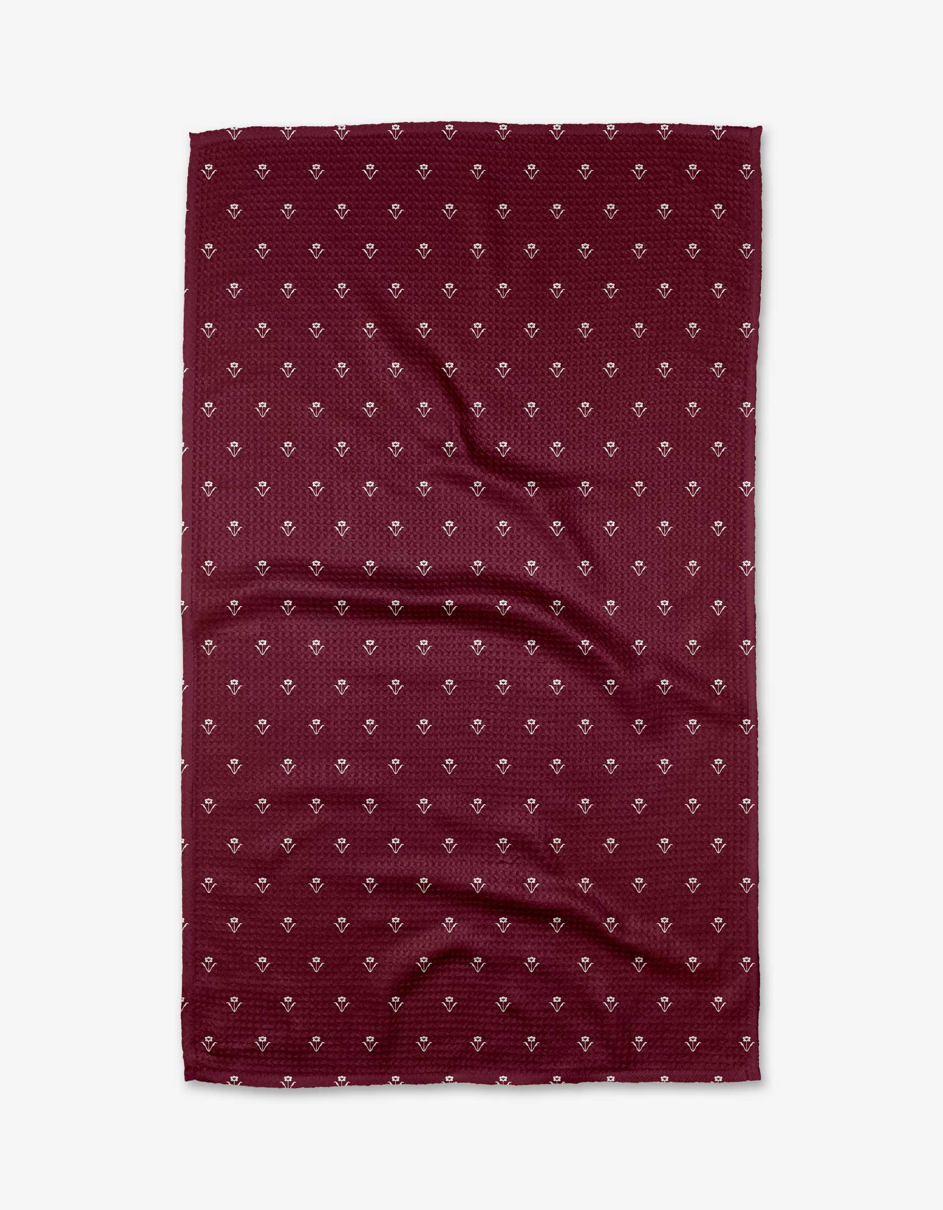 The Buy Guide’s Flowerfield Wine tea towel features a flat, rectangular maroon design with a subtle texture and repeating small white geometric pattern. Made from soft Geoweave fabric, it has slight wrinkles and is shown on a white background.