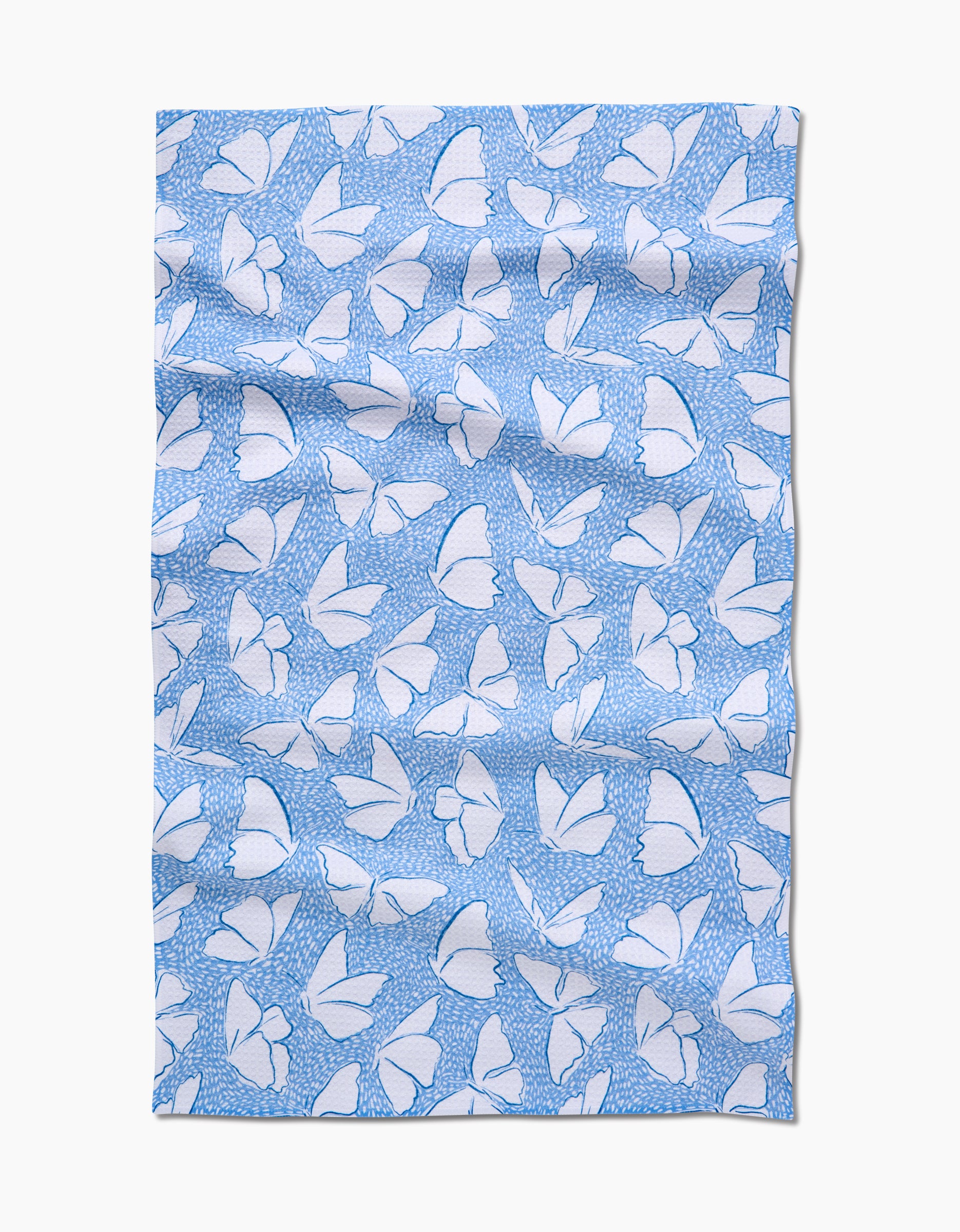 The Fly Away Butterfly tea towel by Hufton Studio features a light blue Geoweave fabric with white butterflies and delicate blue dots, elegantly displayed in soft folds.