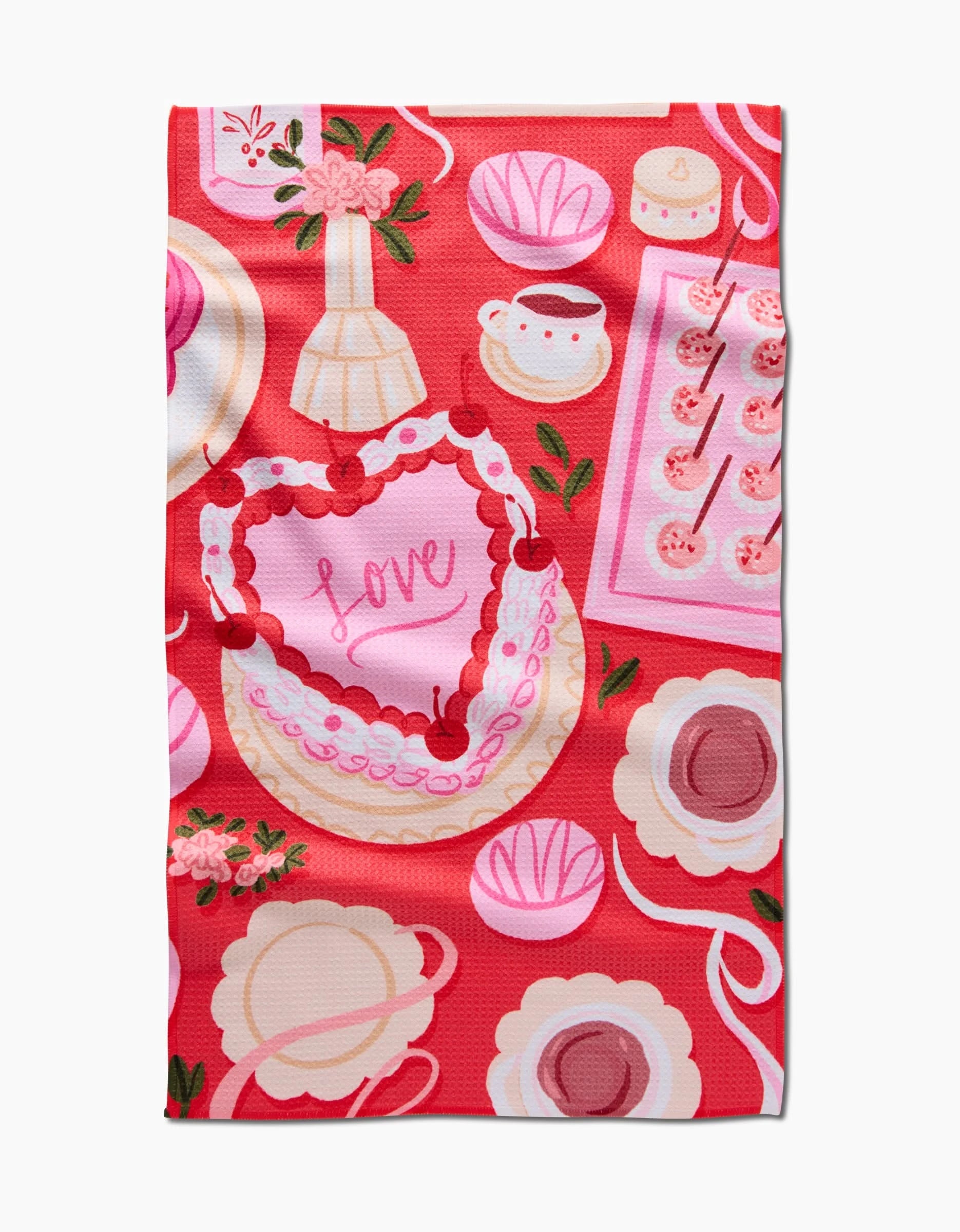 The Food of Love tea towel by Janna Sue Design features ultra-absorbent pink and red fabric with heart-shaped cakes, teacups, flowers, pastries, and a central heart cake with Love in icing on a bright red background.