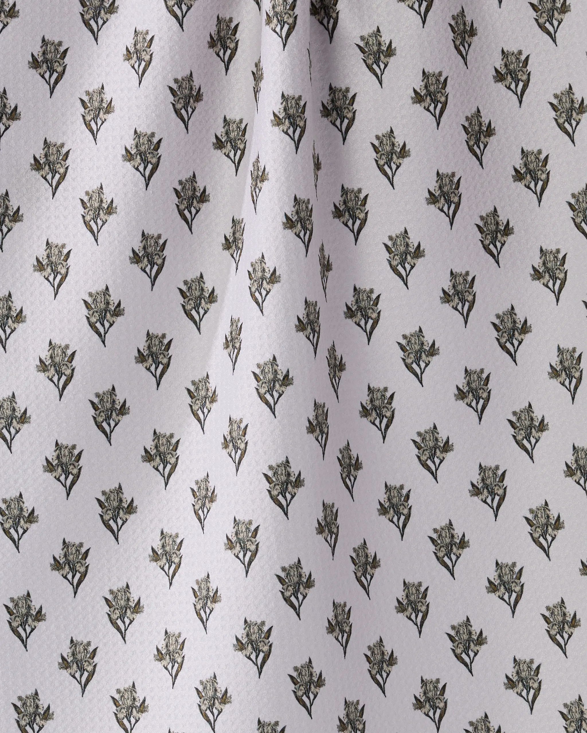 Close-up of Geometry’s Foraged kitchen towel in light grey, featuring a repeating pattern of small dark green leafy branches. Subtle folds add texture to this ultra-absorbent, recycled towel.