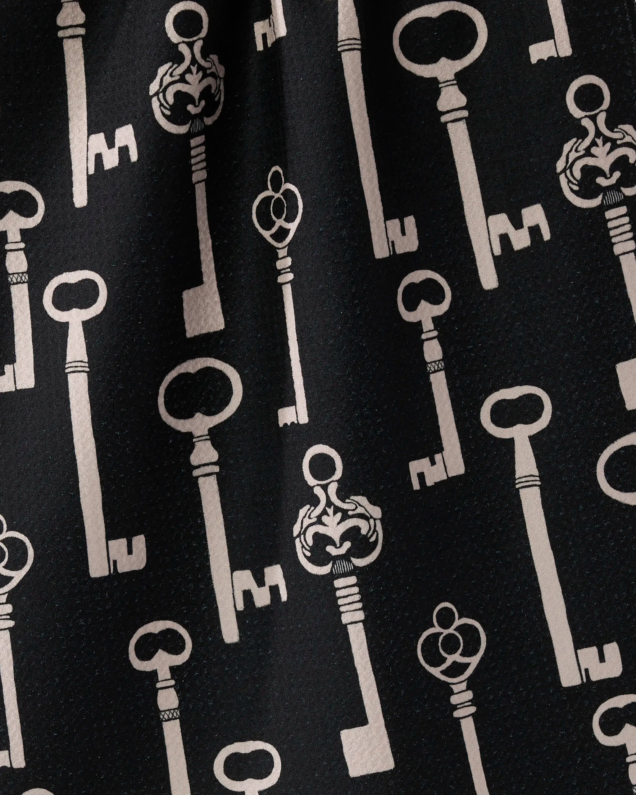 Geometry's "Forbidden Doors" is a black kitchen tea towel with vintage-style white keys in a vertical, even pattern. Made from ultra-absorbent recycled material, it offers both style and sustainability.