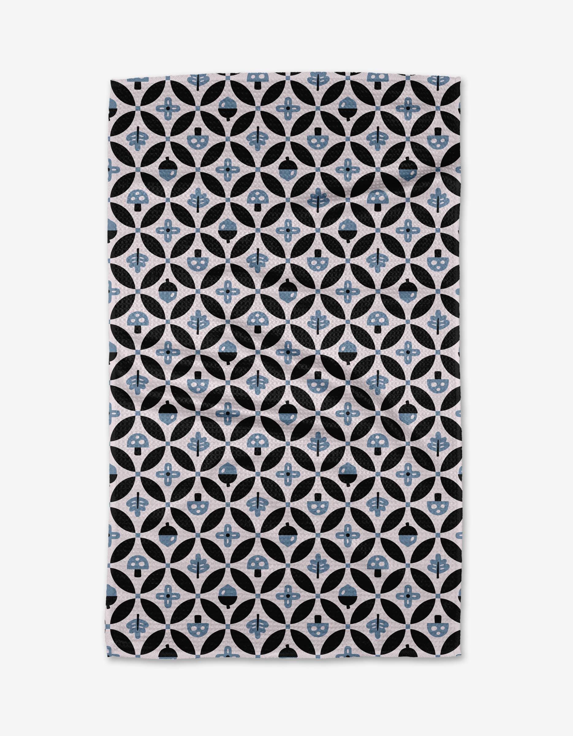 The Anette Heiberg Forest Findings Tea Towel showcases a repeating geometric pattern of black and white circles with blue floral shapes on Geoweave™ fabric, forming a symmetrical, lattice-inspired design.