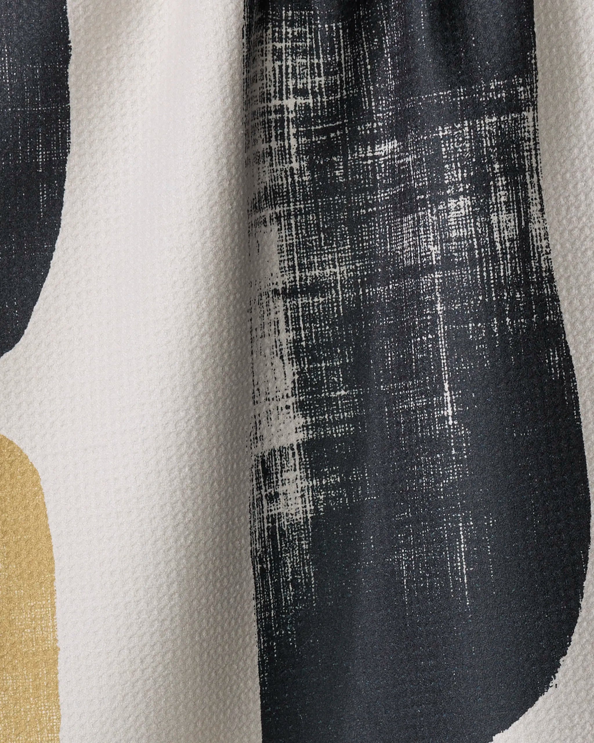 A close-up of Forma by Geometry: an off-white recycled kitchen towel with a textured surface, abstract black distressed shapes, and a small beige accent.