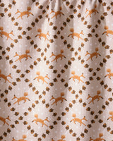 The Foxes and Twinkles tea towel by Geometry features eco-friendly beige fabric with orange foxes, brown acorns, and white stars in a diagonal pattern, plus a subtly textured look and gentle folds at the top.
