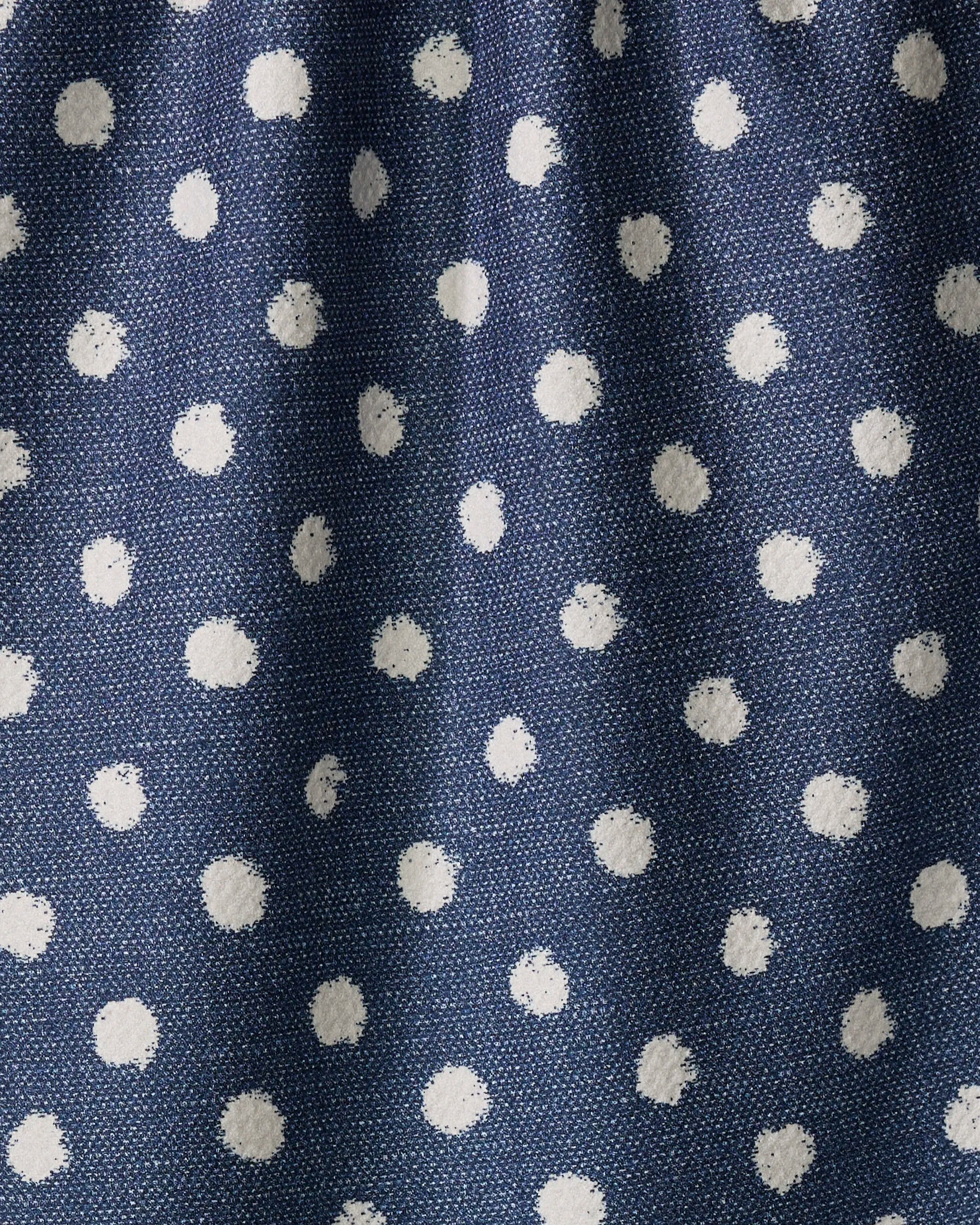 Close-up of Geometry's Freckle Jean tea towel, featuring blue recycled fabric with a white polka dot pattern. The textured material is softly gathered, highlighting gentle folds and shadows.
