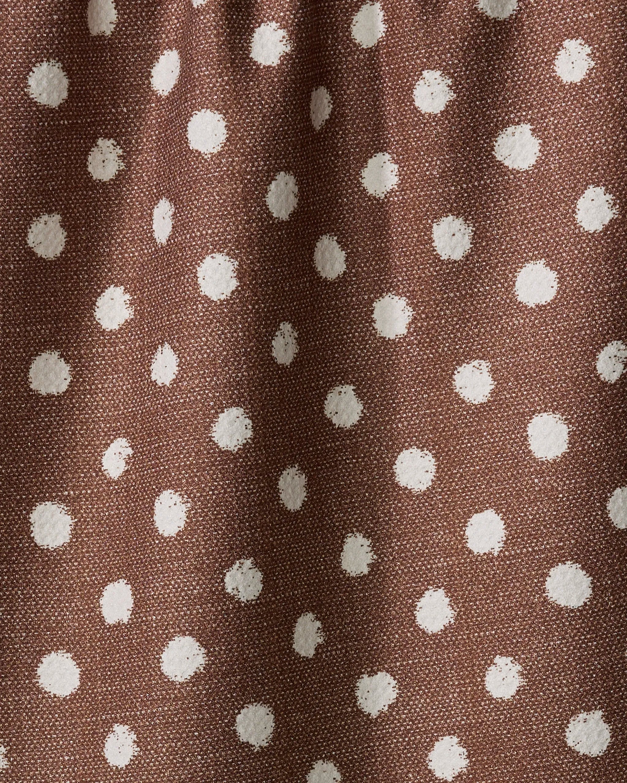 A close-up of the Geometry Freckle Off White tea towel, featuring a brown fabric with a white polka dot pattern and subtle wrinkles.