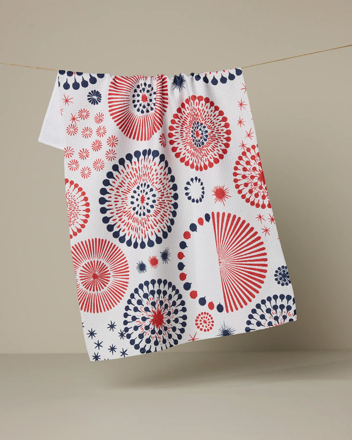 The Geometry Freedom Sparks tea towel features red and blue firework-style circles on white, hanging against a neutral background.