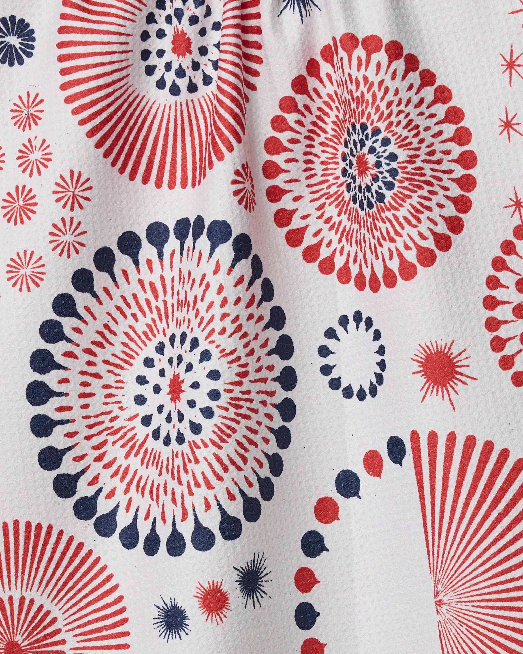 The Freedom Sparks towel by Geometry features red and blue circular bursts on a white textured background, creating a festive and dynamic quick-drying design.