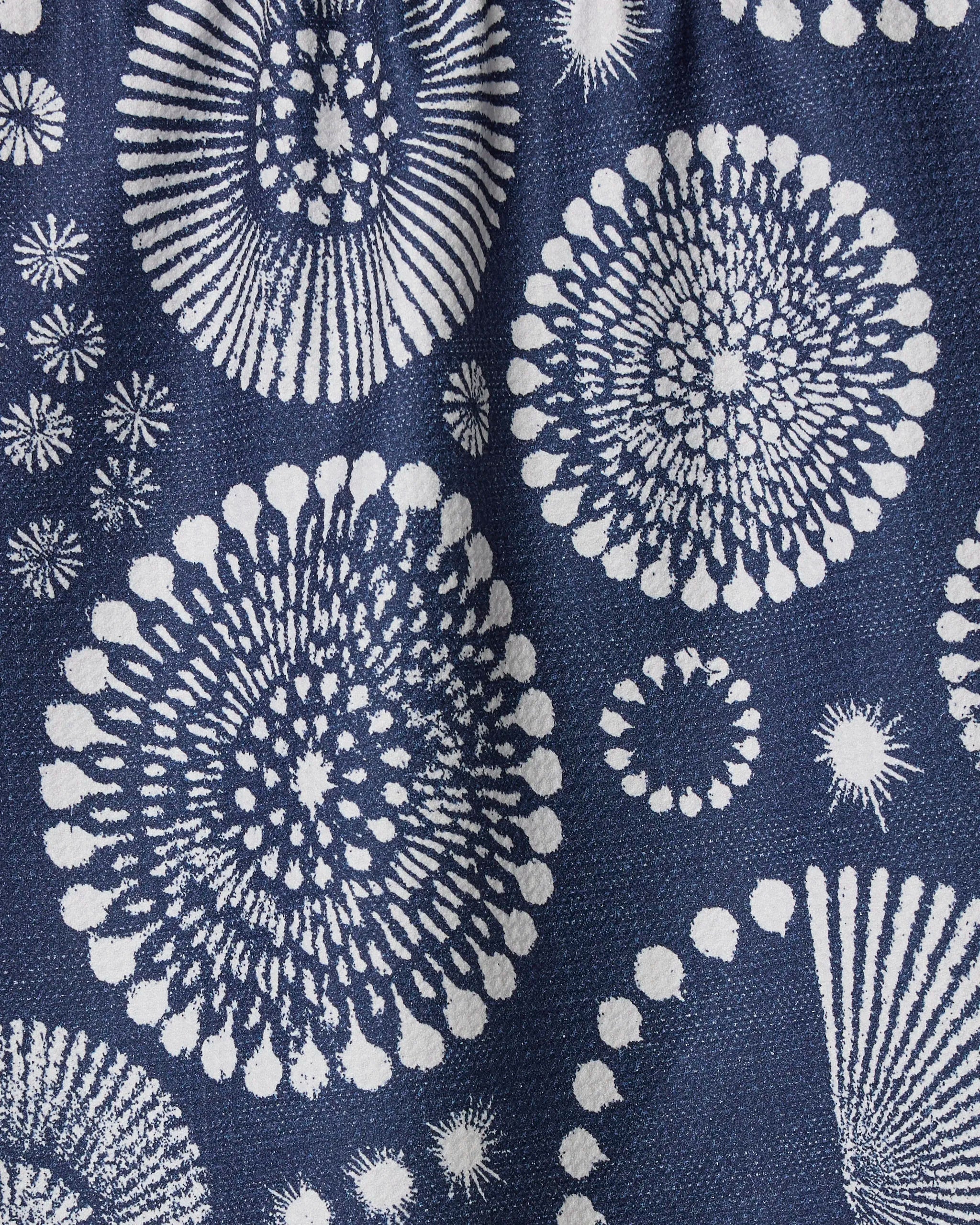 The Freedom Sparks tea towel by Geometry features striking white circular patterns on a dark blue background, offering a bold and textured design that's perfect for adding modern style to any kitchen.