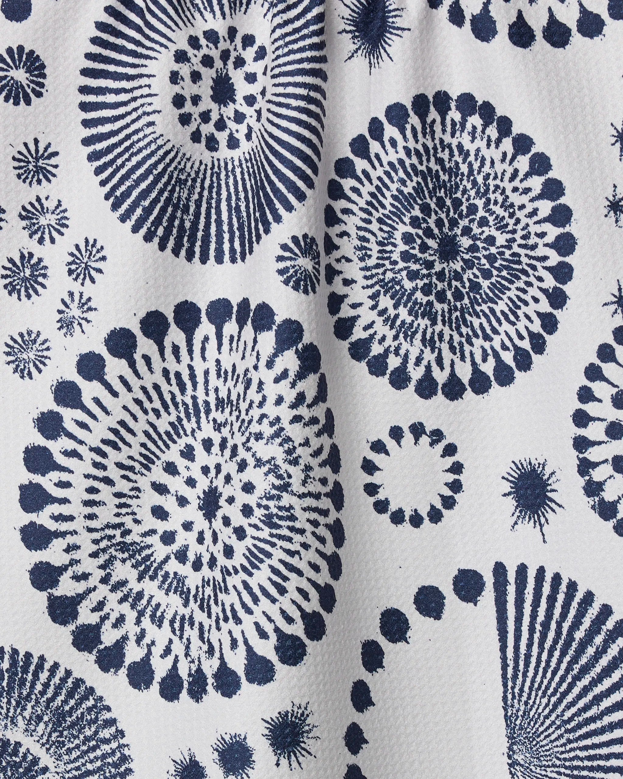 The Freedom Sparks towel by Geometry features navy blue, abstract sea urchin-inspired circles in various sizes on a white textured background. Its quick-drying fabric displays irregularly arranged, overlapping patterns for a modern look.