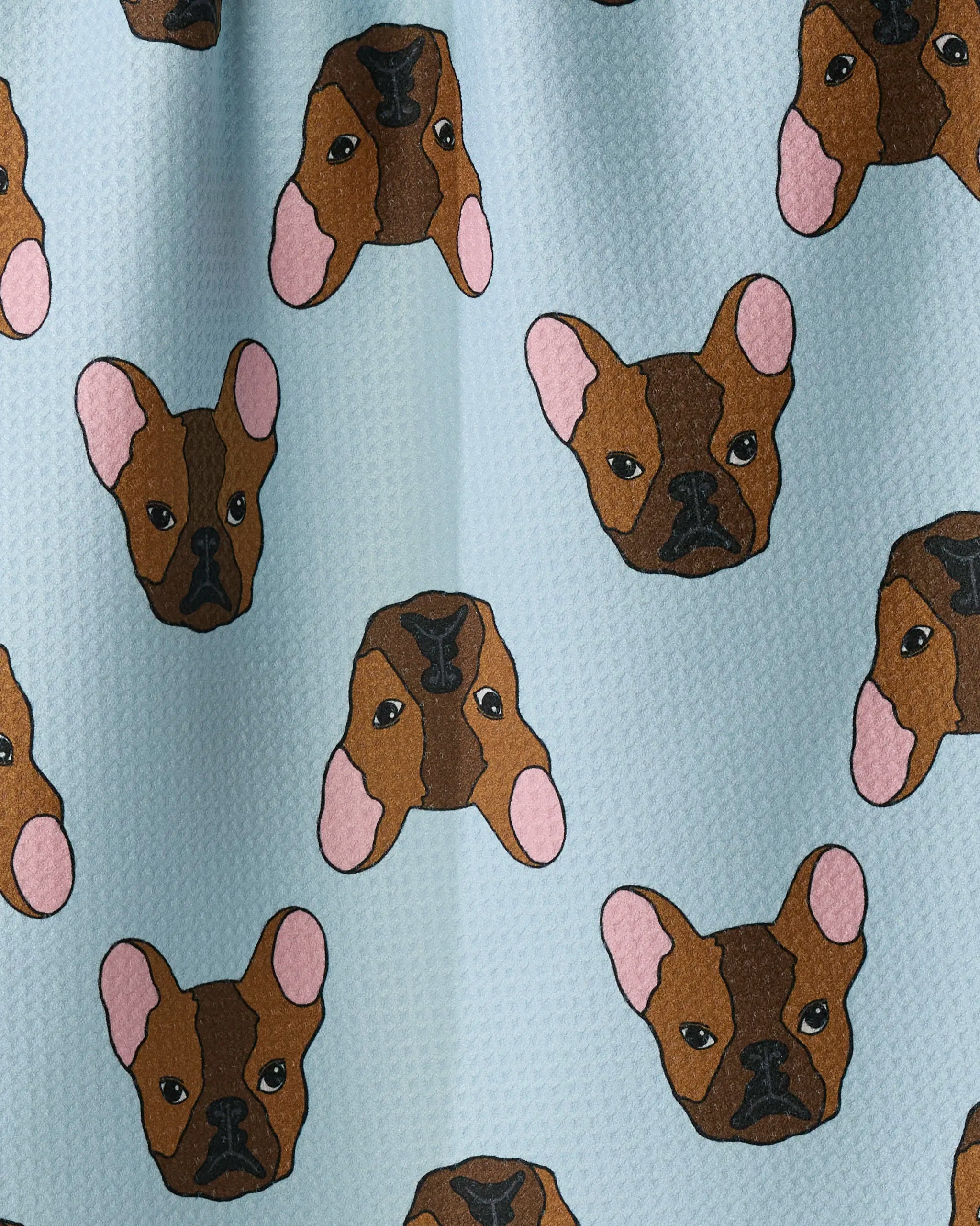 The “Frenchie Faces” kitchen tea towel by Geometry showcases a playful pattern of cartoon French Bulldog faces—with brown fur, pink ears, and black noses—on a light blue background. Crafted from recycled materials, this ultra-absorbent towel blends eco-friendly function with whimsical charm.