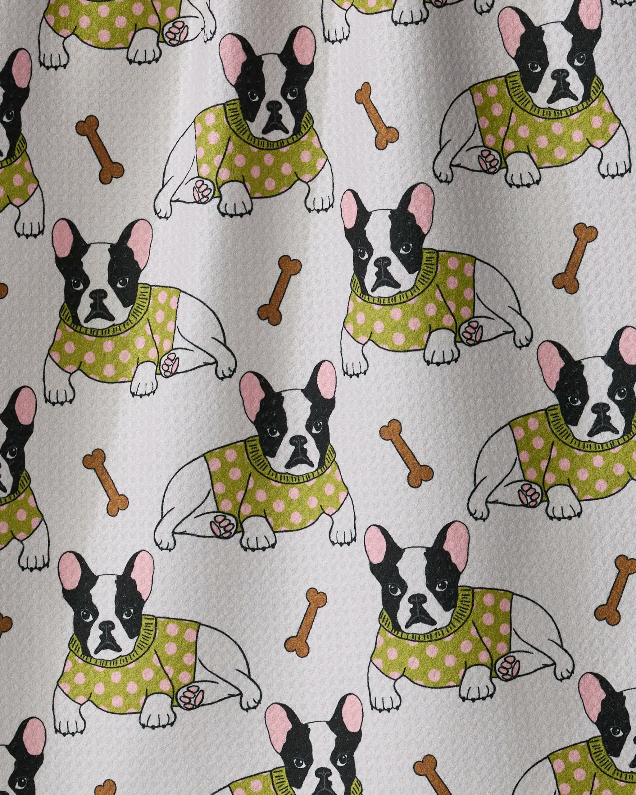 Frenchie Fun by Geometry features a playful pattern of cartoon French Bulldogs in green polka-dot sweaters, lying beside pink balls and surrounded by scattered dog bones on a light background. This delightful design is perfect for adding a touch of whimsy to your kitchen as a cheerful tea towel or an absorbent dish towel.