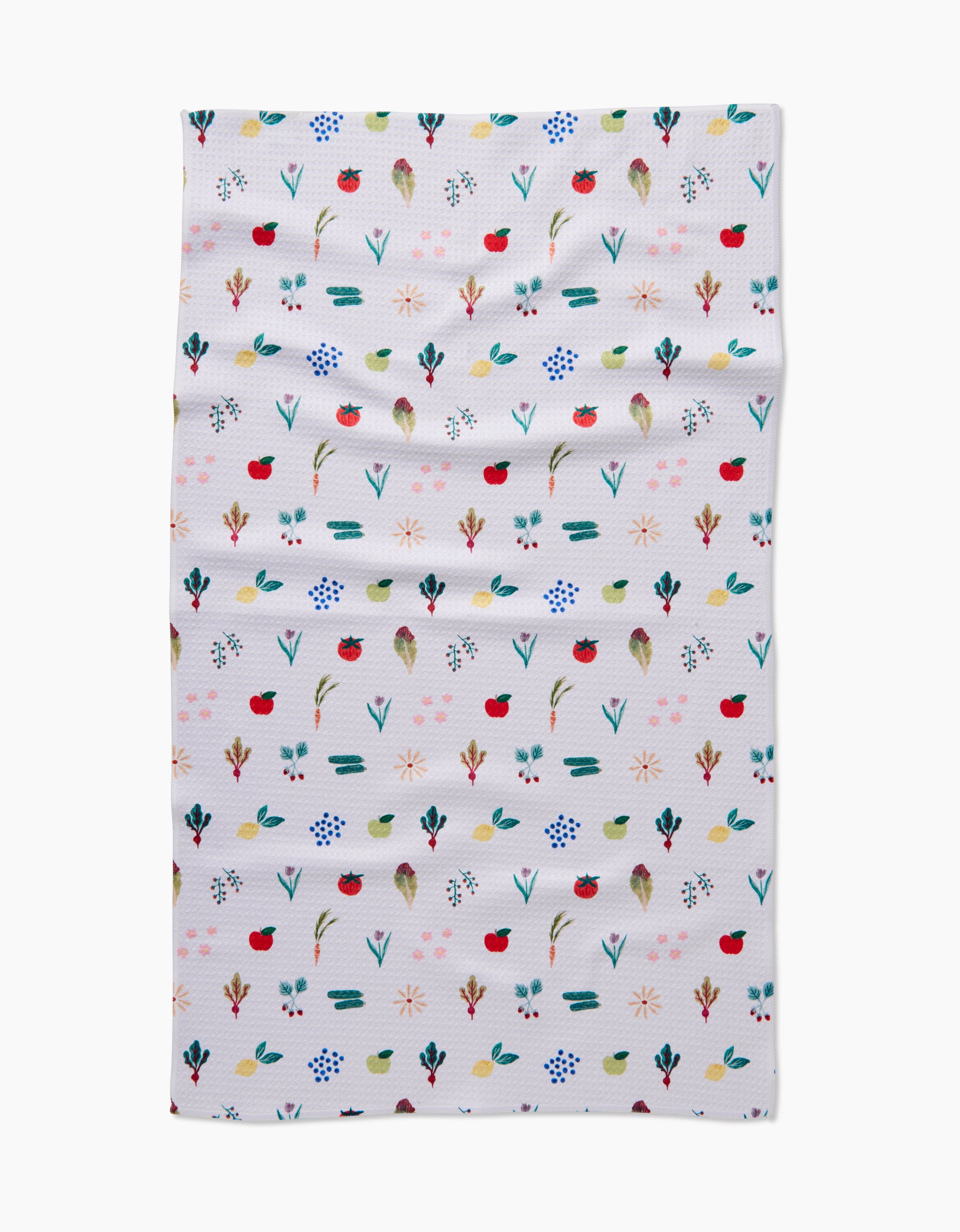 The Brittany Jepsen Fresh Produce tea towel features small, colorful red, blue, green, and yellow flowers and leaves arranged in neat rows on white fabric with a slightly wrinkled texture.