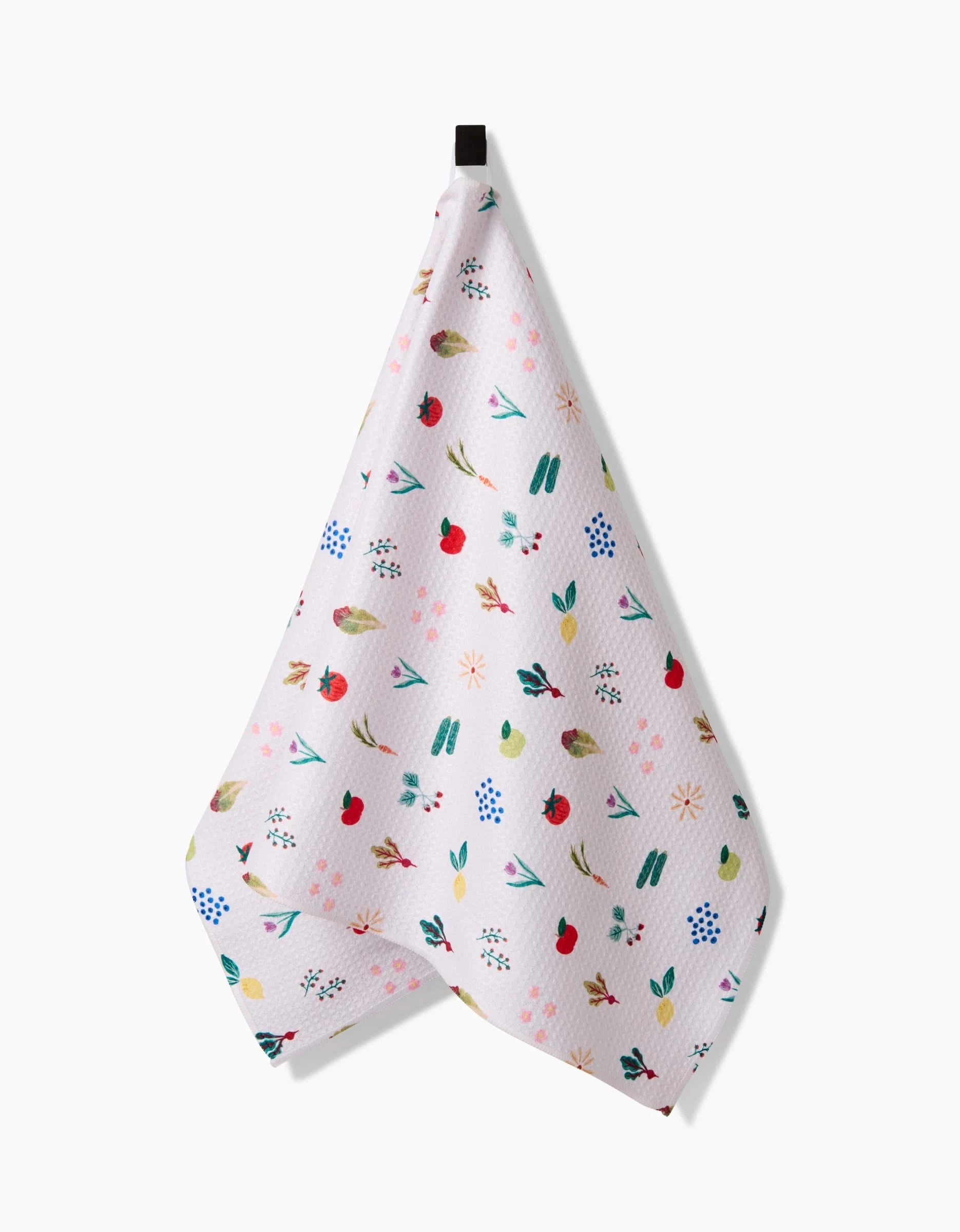 The Fresh Produce tea towel by Brittany Jepsen features a colorful pattern of flowers, fruits, and leaves on white Geoweave fabric, known for its absorbency and durability. It hangs by a loop against a plain white background.