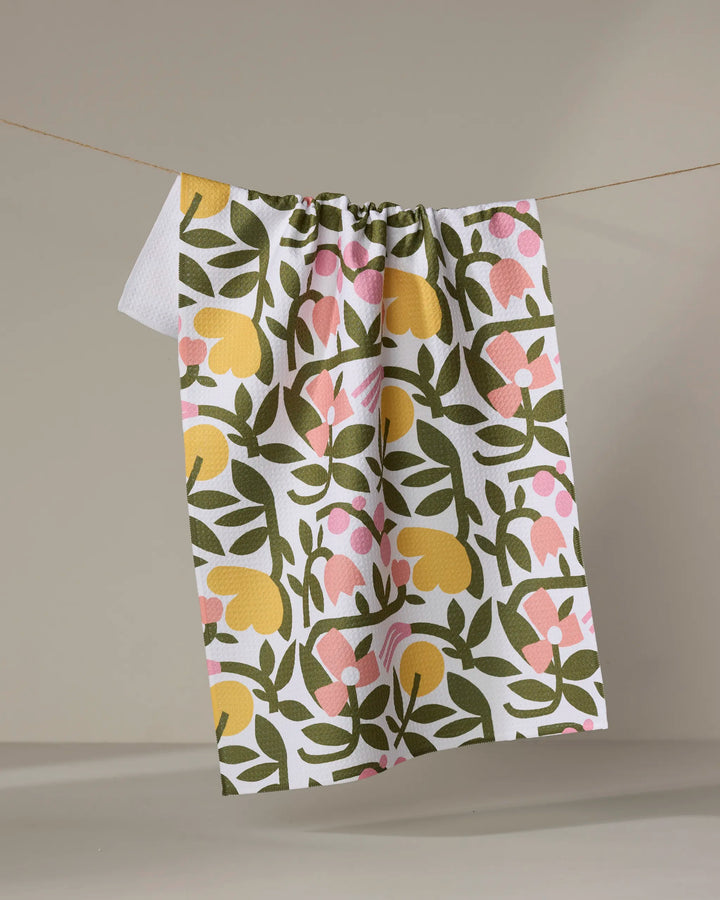 The Fresh Vines tea towel by Lisa Nelson features a colorful green, yellow, and pink floral pattern on white Geoweave fabric. It hangs on a beige string against a neutral background, perfect for everyday use.
