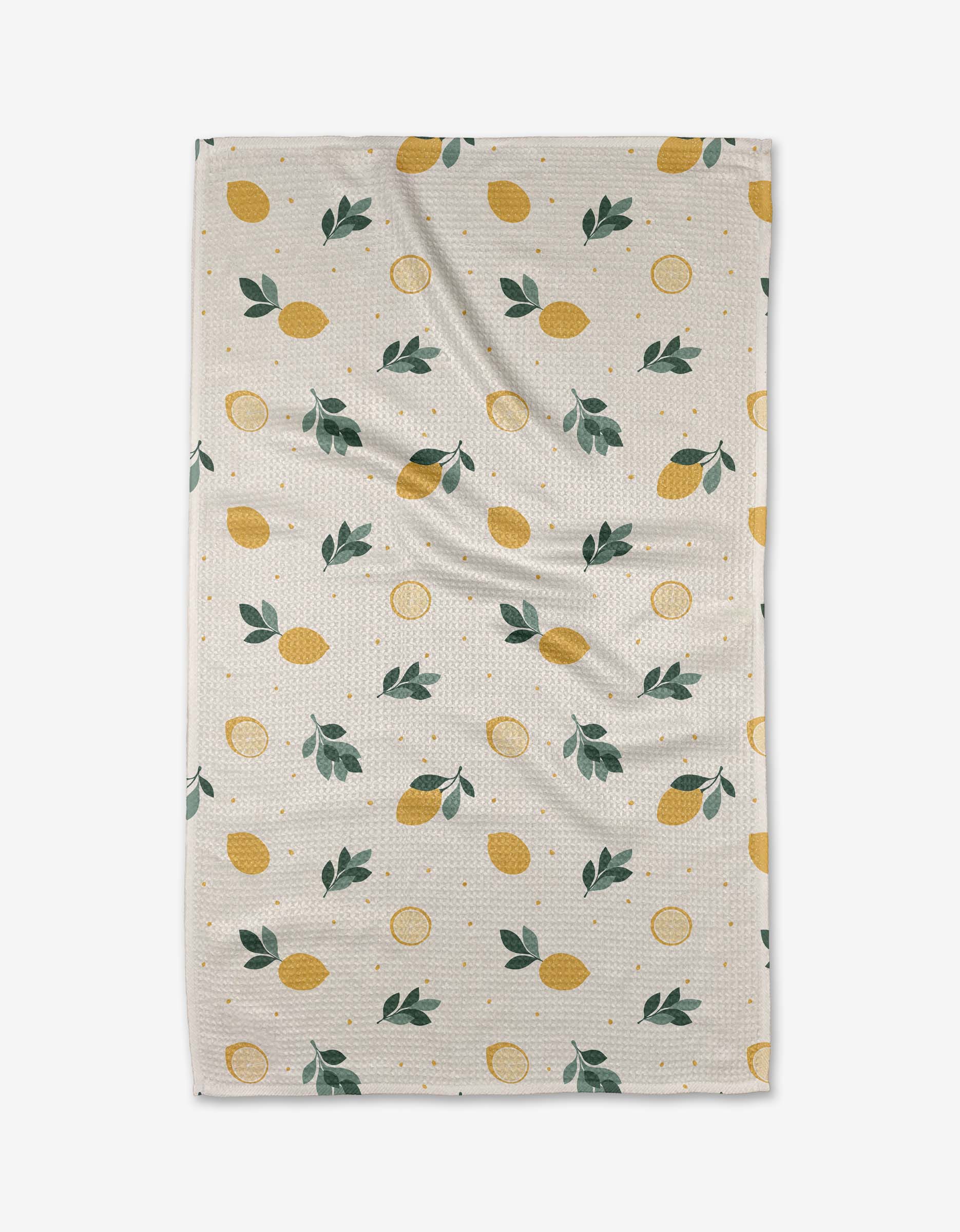 The Freshly Picked tea towel by Sara Mari features a beige recycled fabric with a textured finish, decorated with yellow lemons, green leaves, and orange dots in a repeating pattern and displayed slightly wrinkled.