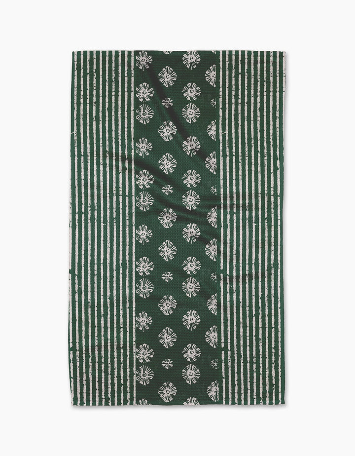 The Freya tea towel by Geometry features vertical green and white stripes with a central panel of white floral motifs on green, crafted from durable Geoweave fabric.