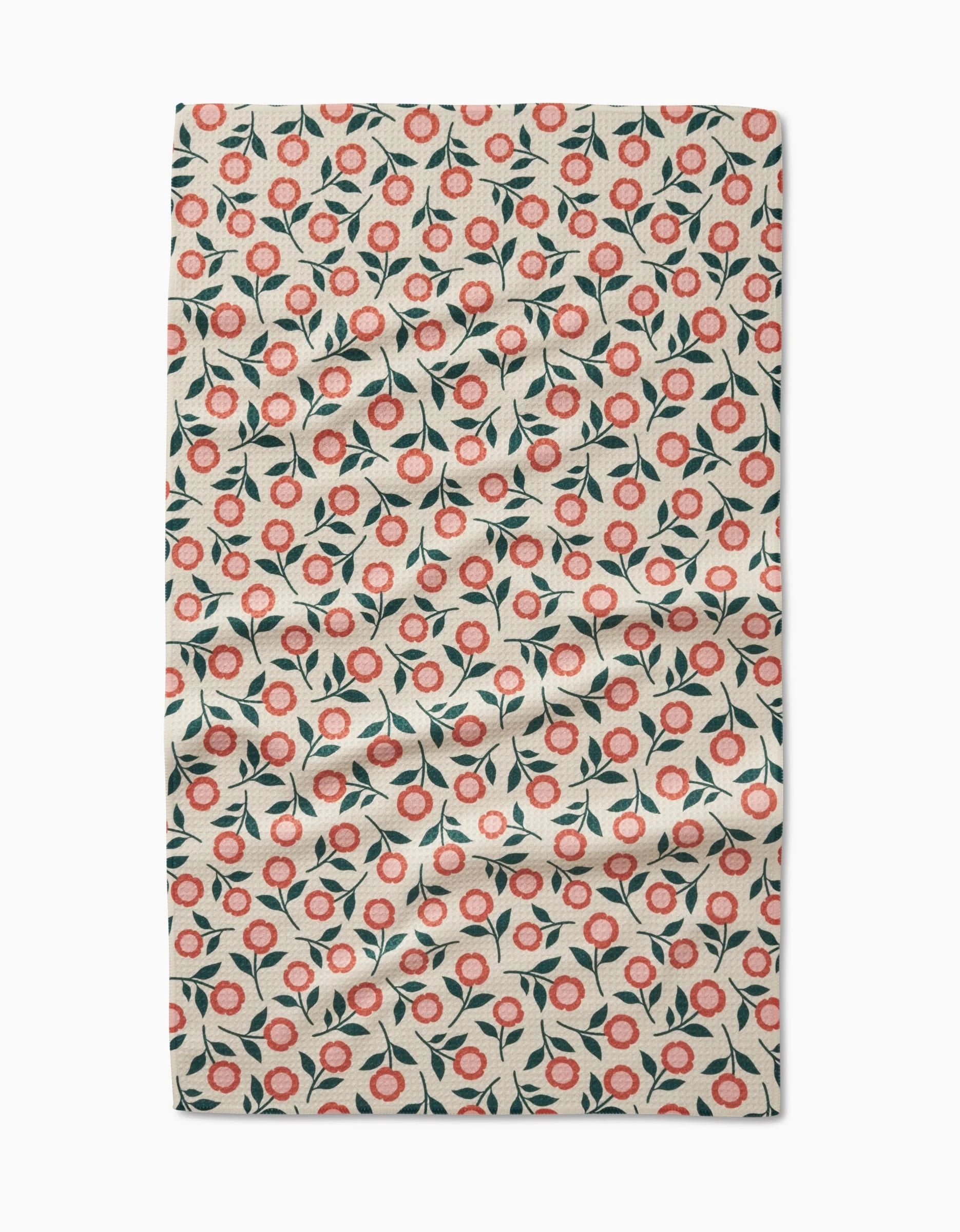 Friendly Floral Peach by Megan Kampa features a Geoweave fabric with small red and pink flowers, green leaves, and a light beige background. This ultra-absorbent towel may show some visible creases and folds.