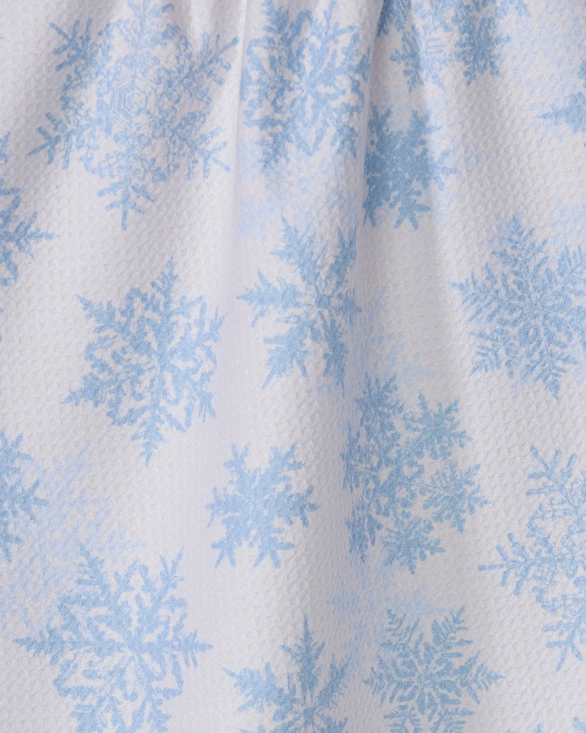 The Geometry Frostin kitchen towel is crafted from recycled materials and features a slightly textured white fabric adorned with light blue snowflakes in various shapes and sizes, perfect for a charming winter-themed touch.