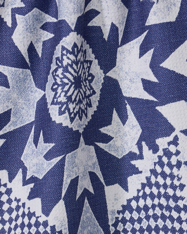 Close-up of Geometry’s Froststar kitchen towel featuring a blue and white geometric star pattern with jagged edges and a central floral motif, made from textured recycled materials.