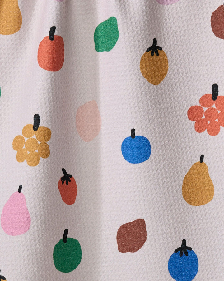Fruit Basket by Jennifer Bouron is a textured white tea towel made from recycled materials, decorated with playful, abstract fruit shapes in pink, green, blue, yellow, orange, and red—each with a simple black stem.