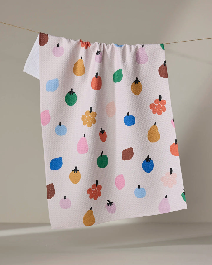 The "Fruit Basket" tea towel by Jennifer Bouron is made from recycled materials and features a lively pattern of colorful apples, pears, berries, and dots on a neutral background, bringing cheerful charm to your kitchen.