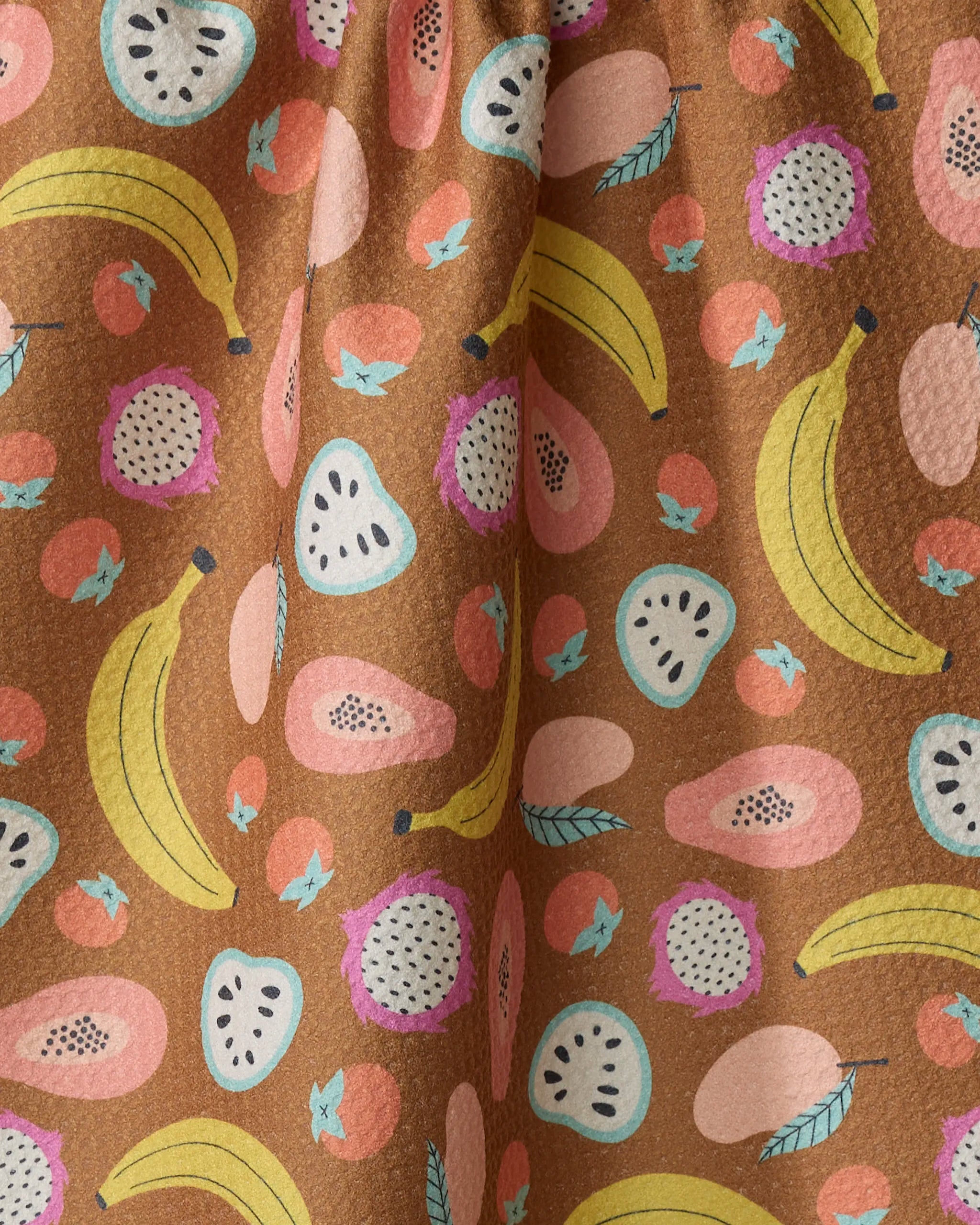 The "Fruit Salad" tea towel by Megan Kampa is brown and features a vibrant pattern of bananas, papayas, guavas, pink berries, green leaves, and small blue birds—an ideal way to brighten up your kitchen.