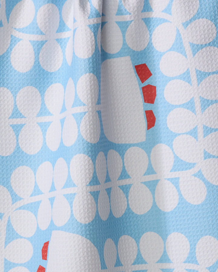 Close-up of the Gemini kitchen towel by Happy Hemera, showcasing its white geometric floral pattern and small red accents on a blue background. Made from recycled materials for an eco-friendly choice.