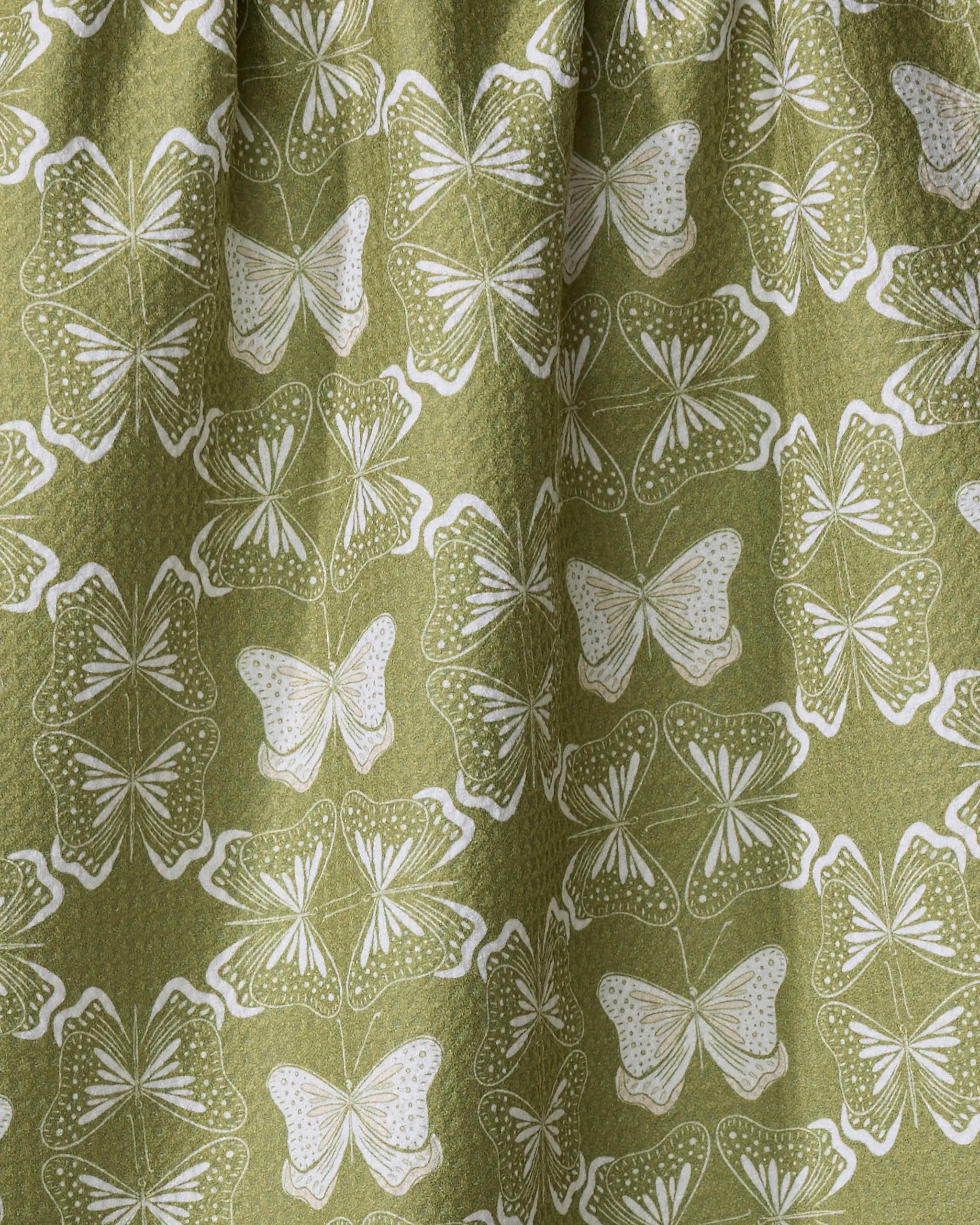 The Geometric Butterflies tea towel by Second Nature Studio features a green fabric with repeating white butterflies in a dotted, symmetrical pattern. Made from quick-drying recycled materials.