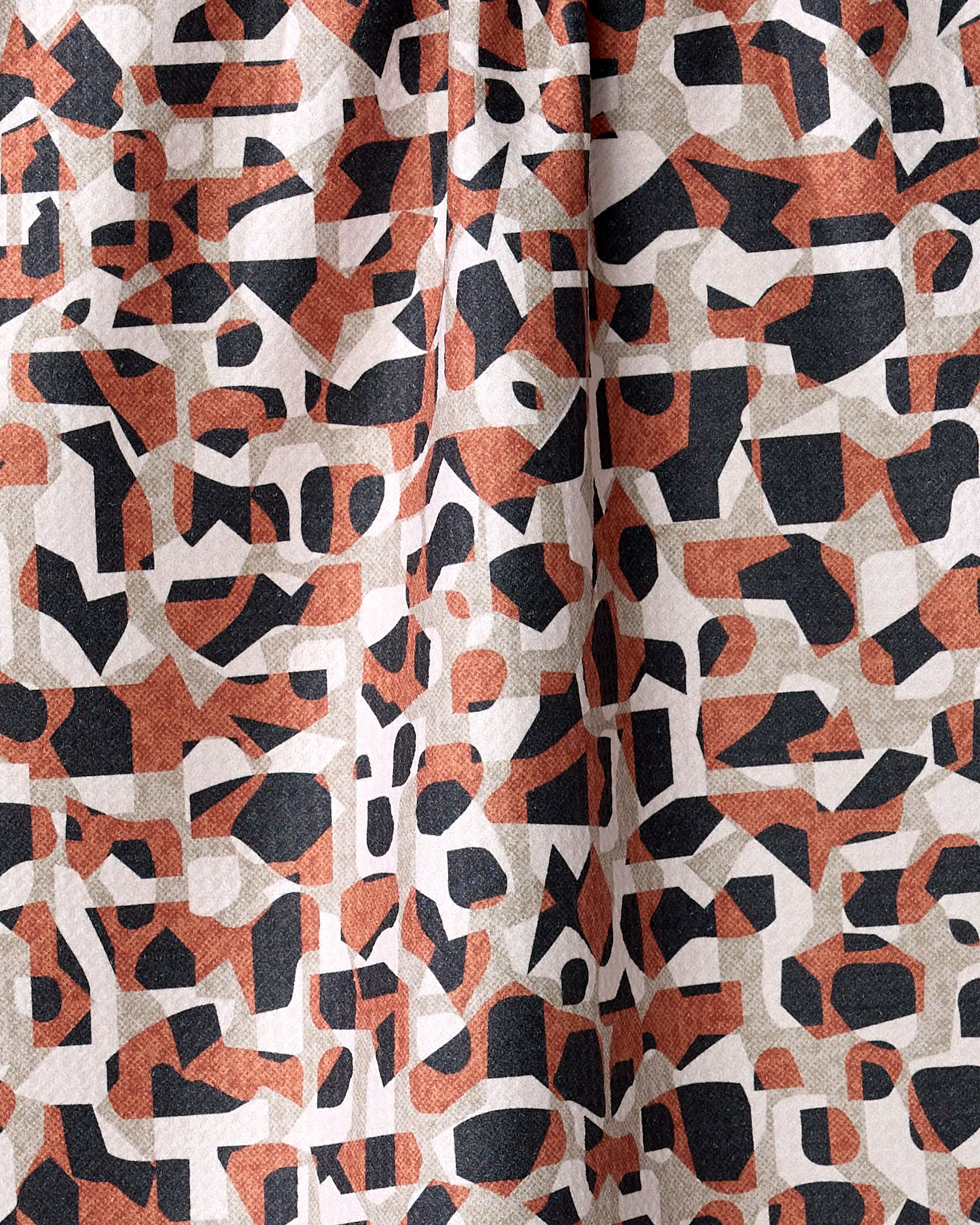 A close-up of Kris Ruff’s Geometric Leopard tea towel showcases abstract black, rust orange, and beige shapes—overlapping polygons and lines that accentuate the ultra-absorbent textured fabric.