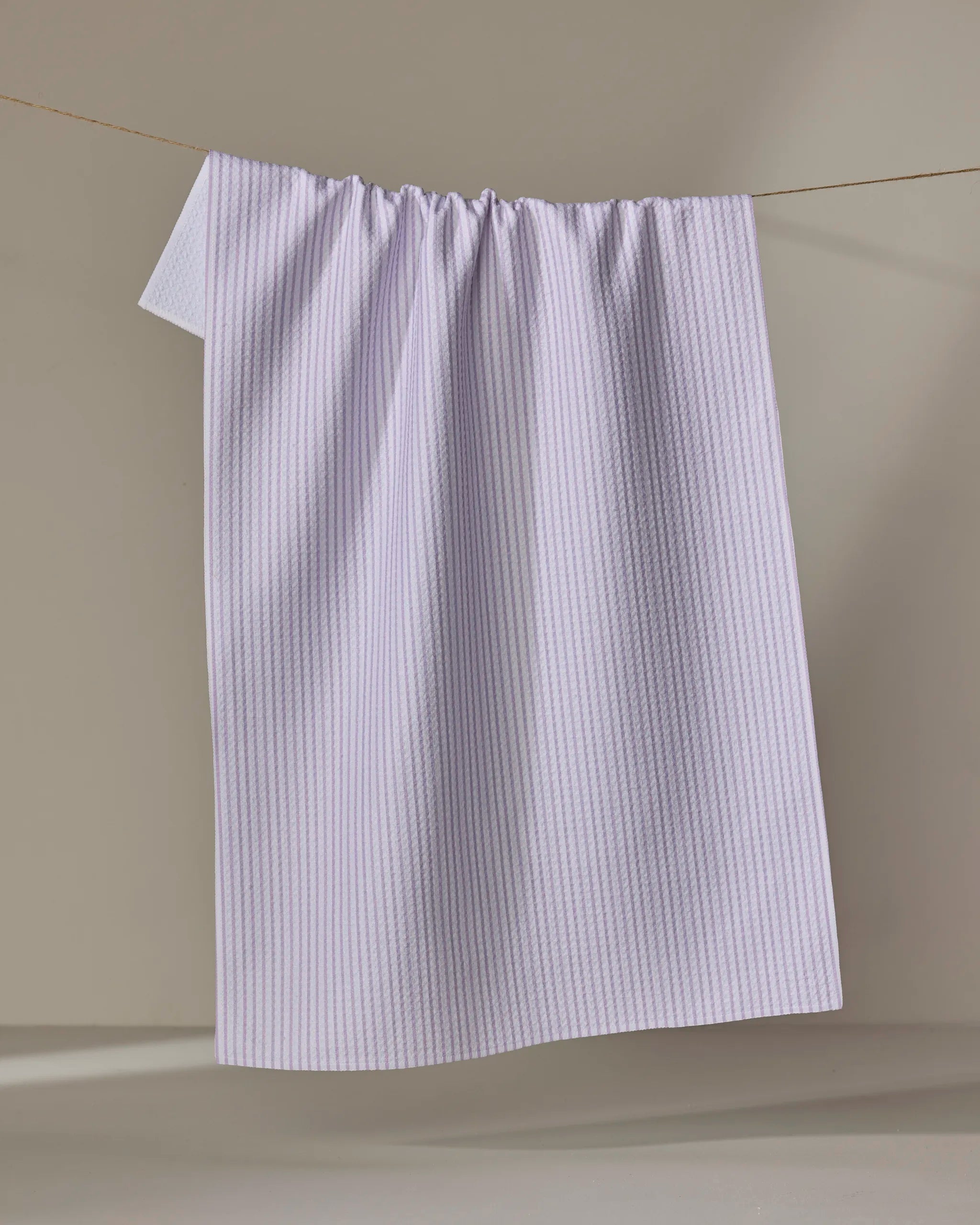 The Buy Guide’s Get In Line - Lilac towel, featuring subtle stripes and ultra-absorbent texture, hangs neatly against a neutral background.