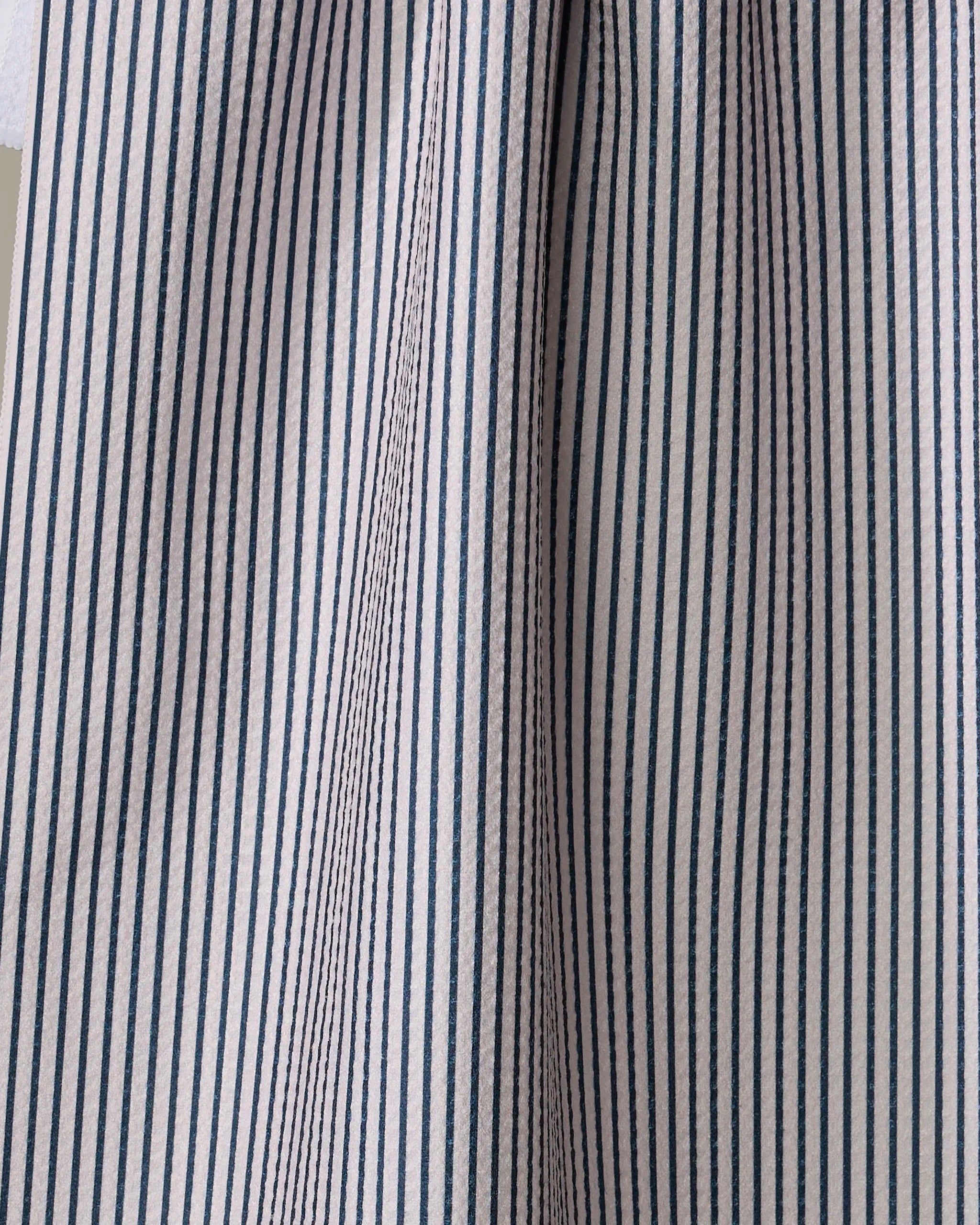 Close-up of The Buy Guide’s Get In Line - Navy towel, featuring blue and white vertical stripes. Ultra-absorbent fabric with soft folds and gentle shadows highlights its textured look.
